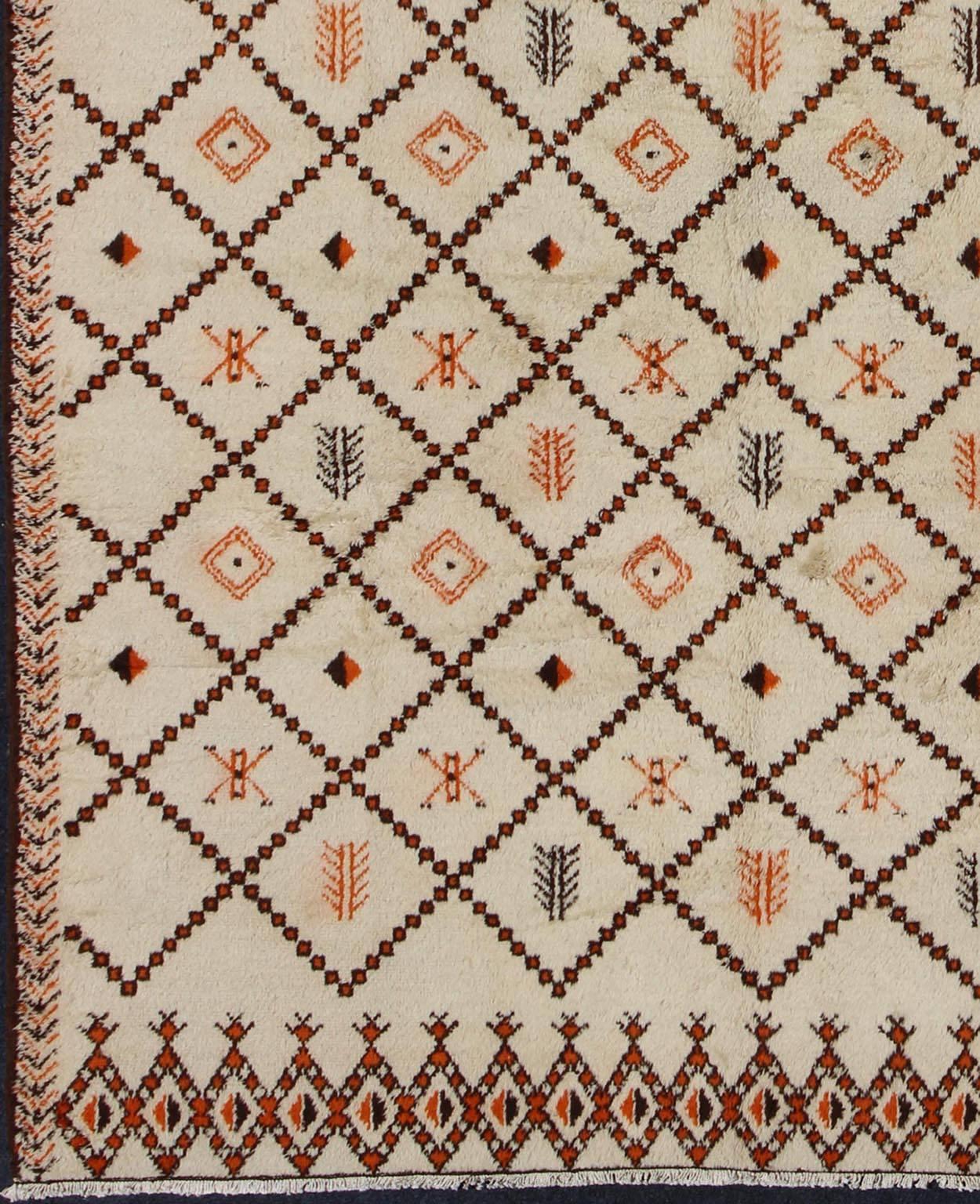 Large Vintage Moroccan Rug in Diamond Design with Ivory and Brown Outlines
This Moroccan rug has an all-over geometric diamond pattern  in Ivory Background with brown and orange outlines. The colors include ivory, orange, black and charcoal.