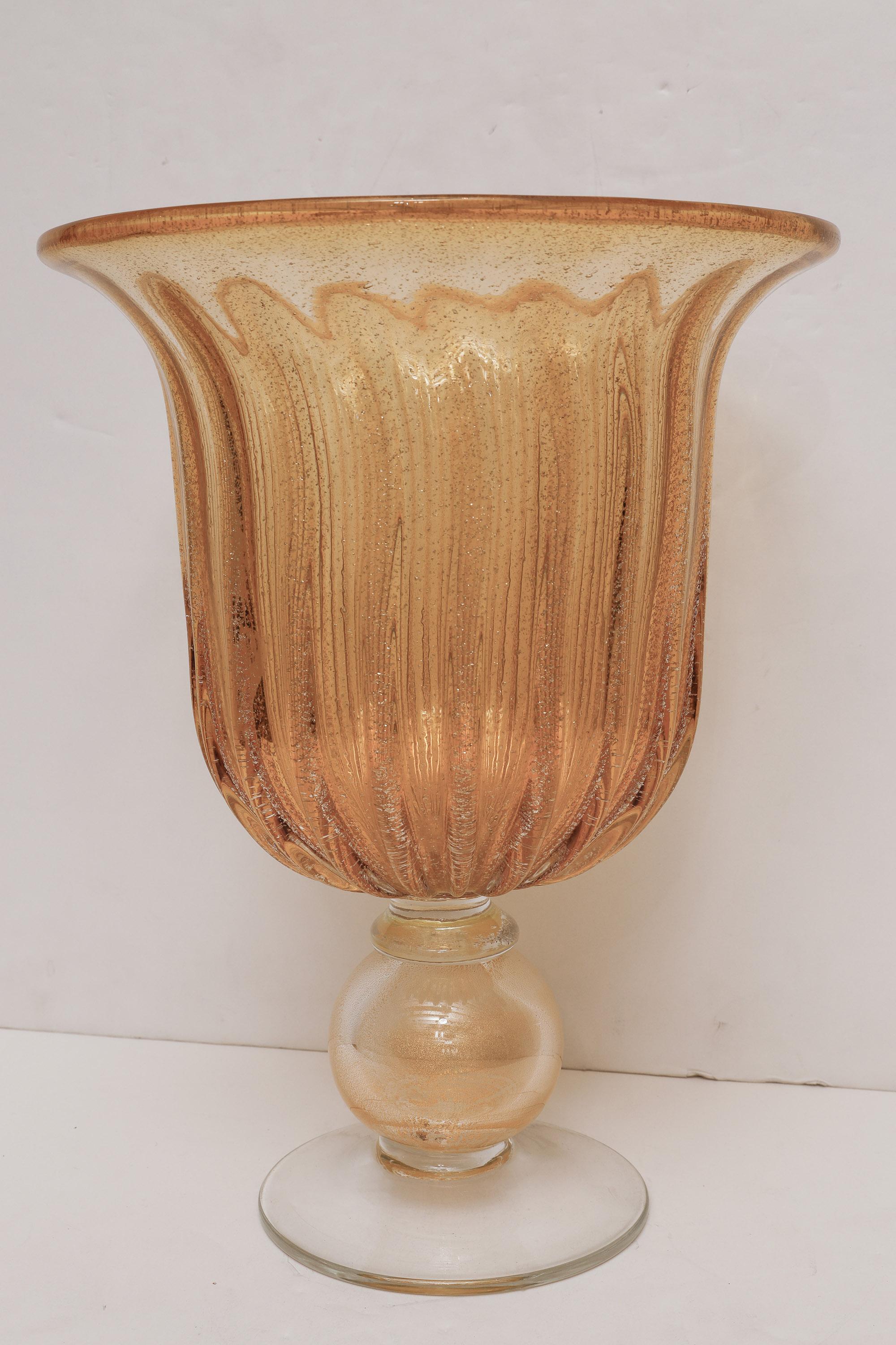 Magnifique vase cannelé soufflé à la main de Murano dans le style d'Angelo Seguso, exécuté en verre ambré et transparent avec de la poussière d'or et des inclusions scintillantes.
De grande taille, il s'agit d'une pièce maîtresse.