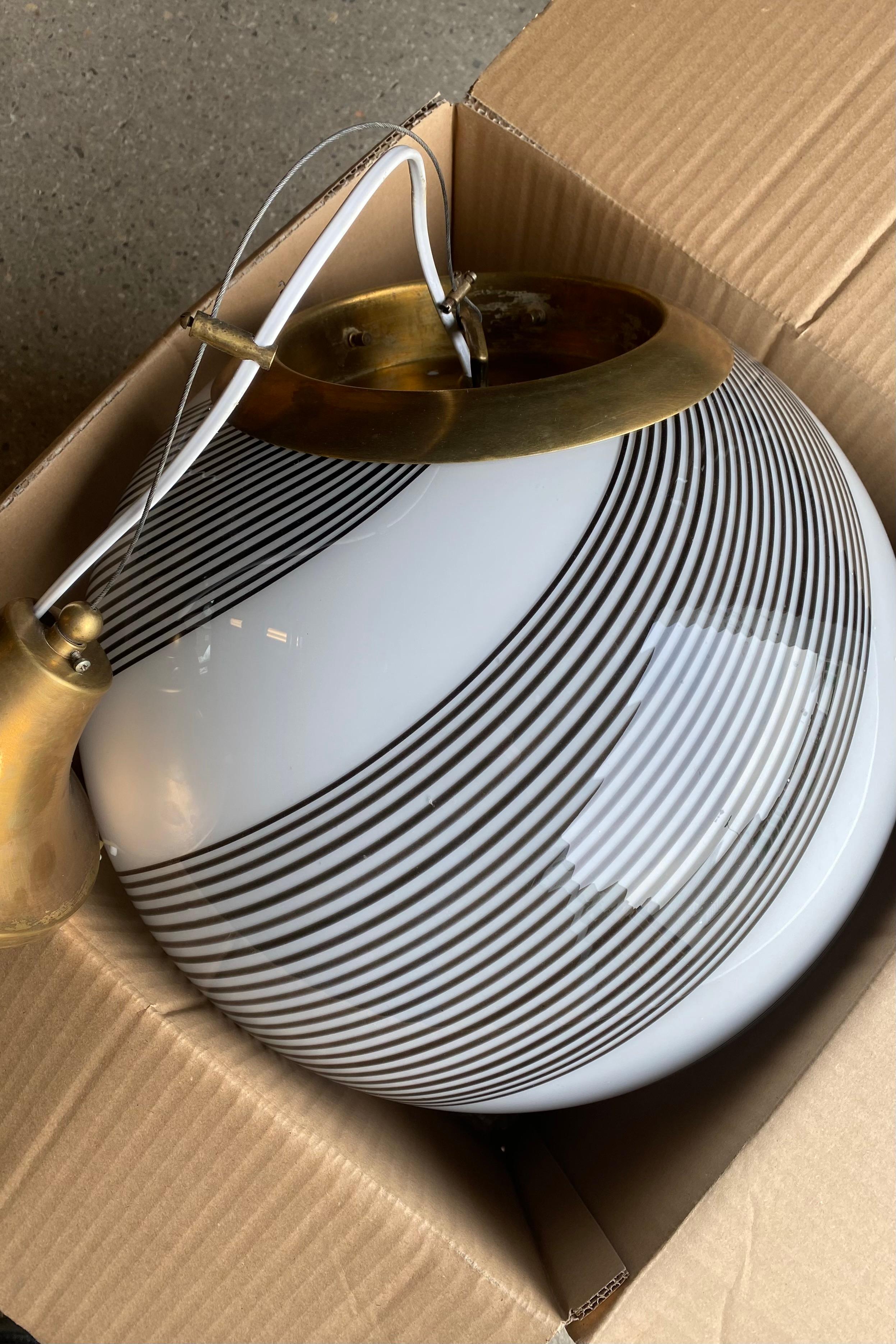 Große hängende Murano-Deckenlampe im Vintage-Stil. Das Glas ist mundgeblasen und hat eine runde Form mit einem schönen Wirbelmuster. Handgefertigt in Italien, 1970er Jahre, mit verstellbarer Messingaufhängung.
T: 40 cm

