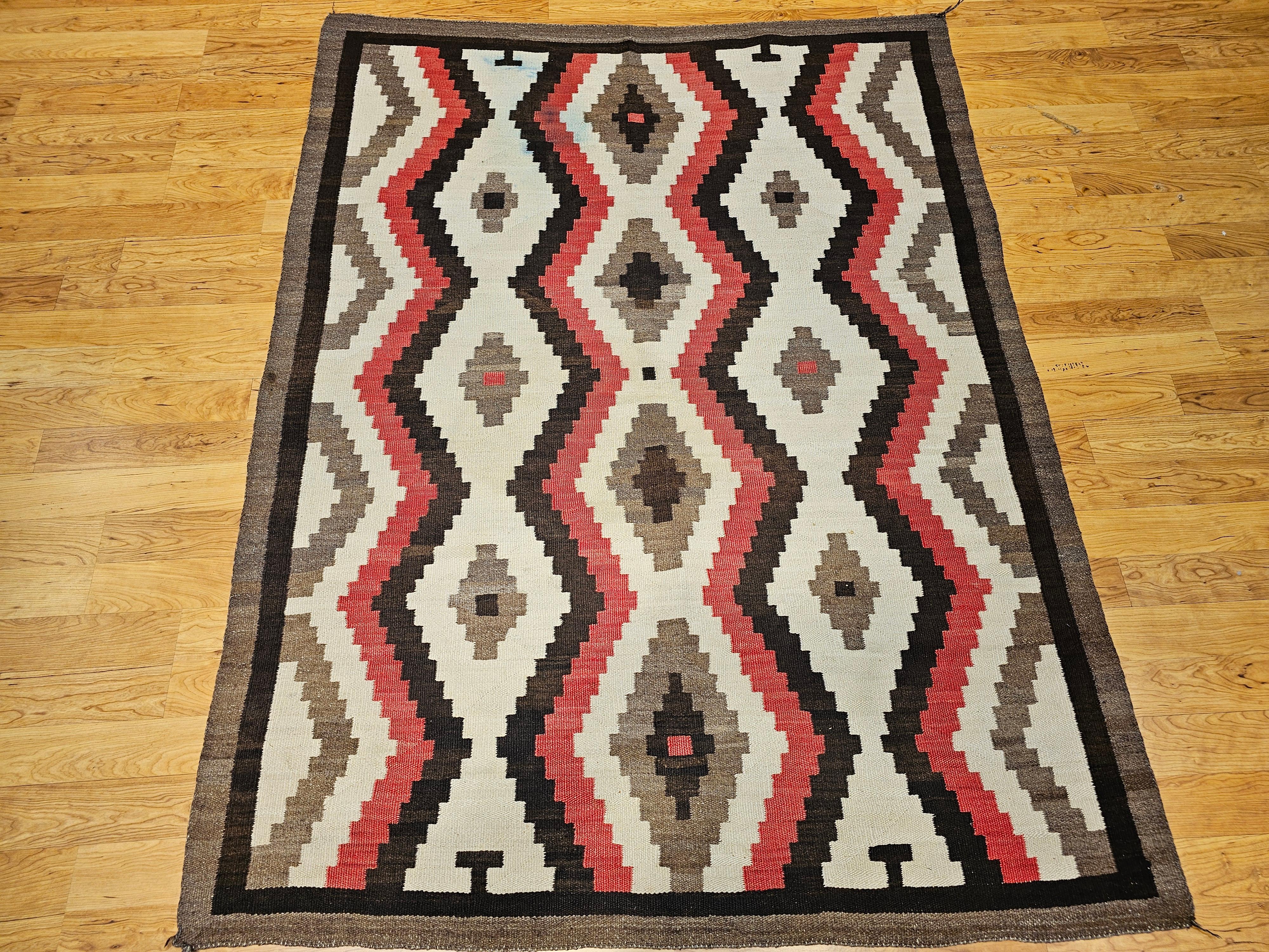 Large size and finely hand-woven Native American Navajo rug in eye dazzler diamond pattern in white, red, brown, and chocolate colors from the SW United States circa the early 1900s.   The pattern displays a series of vertical diamond forms that are