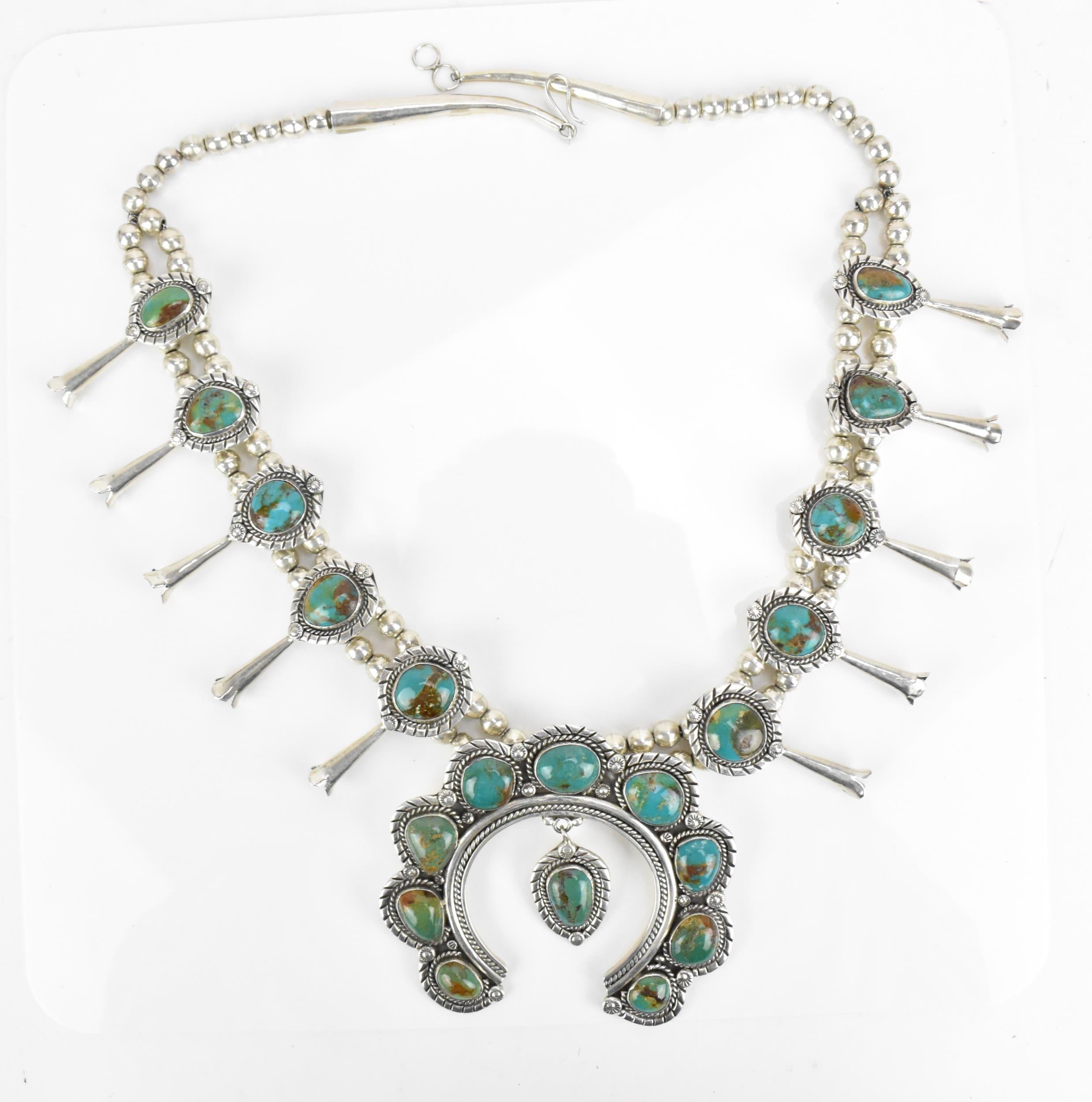 Fine quality large hand crafted Vintage Native American Navajo sterling silver and Turquoise squash blossom necklace.

In the classic Navajo Silver squash blossom design with blue green turquoise inlays

Period: 1980`s stamped sterling with makers