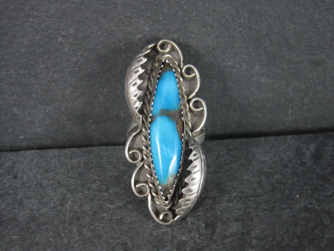 This gorgeous Navajo turquoise ring is done in a traditional style.
It is sterling silver. The turquoise is natural.

The face of this ring measures 3/4 of an inch east to west and 1 3/4 inches north to south.
Size: 8

Marks: OAT

Condition: