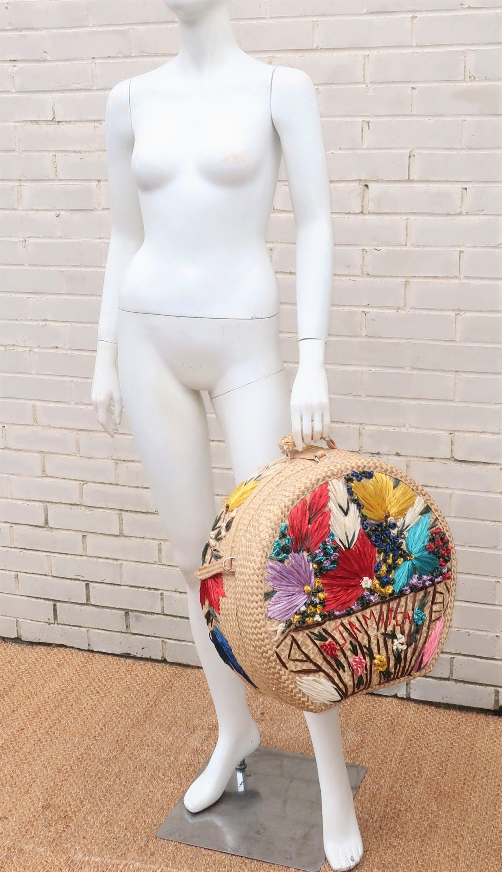 A charming 1960's Jamaican straw beach bag decorated with a colorful floral raffia embroidery.  This beach bag is unusual both due to size and the sturdy construction consisting of buckled straps and silver metal ringed hinges and handle hardware. 