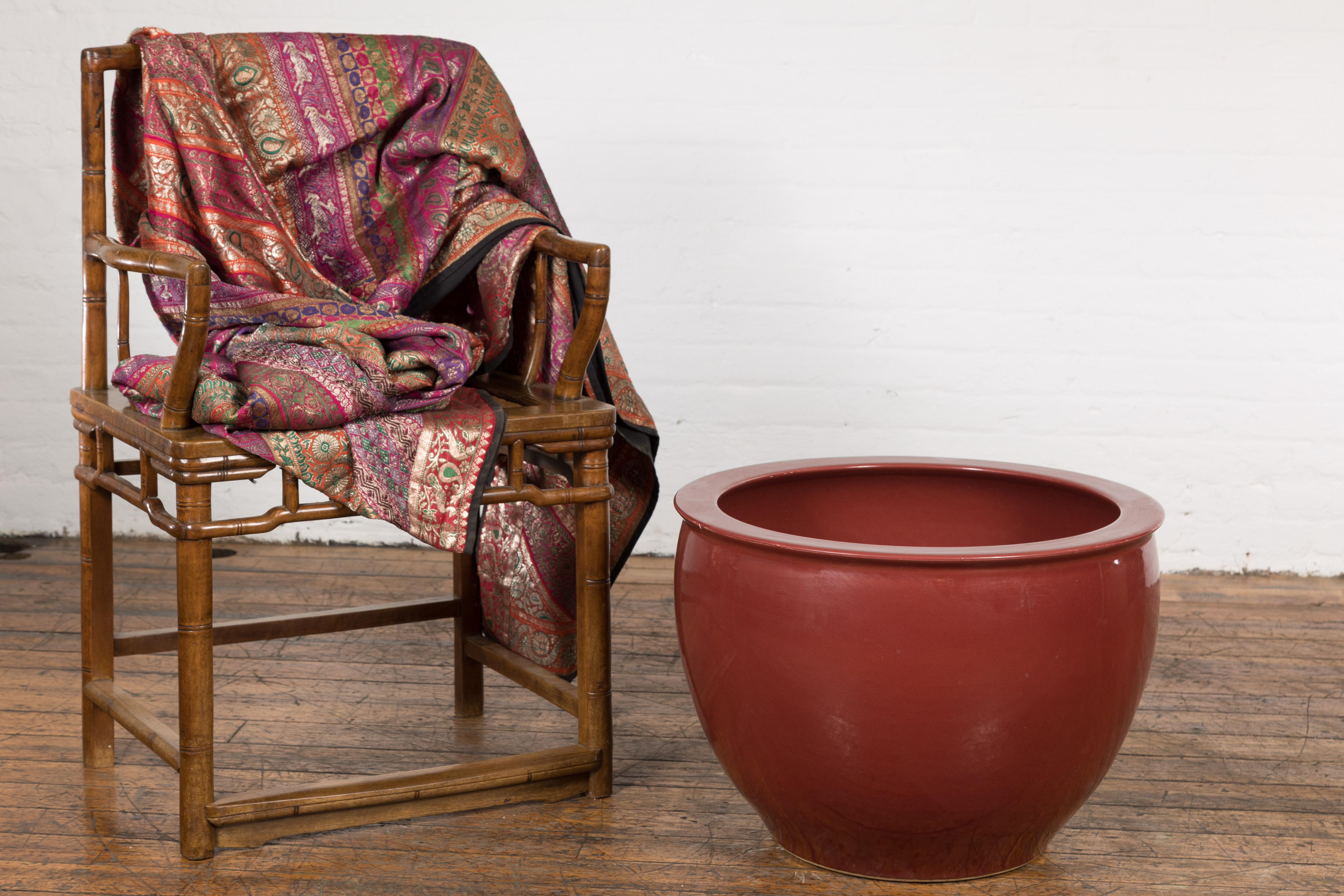 A vintage Chinese oxblood round planter from the mid 20th century with large ring shaped mouth and tapering lines. This vintage Chinese oxblood planter, dating back to the mid 20th century, is a piece that showcases the artistry of Chinese ceramics.