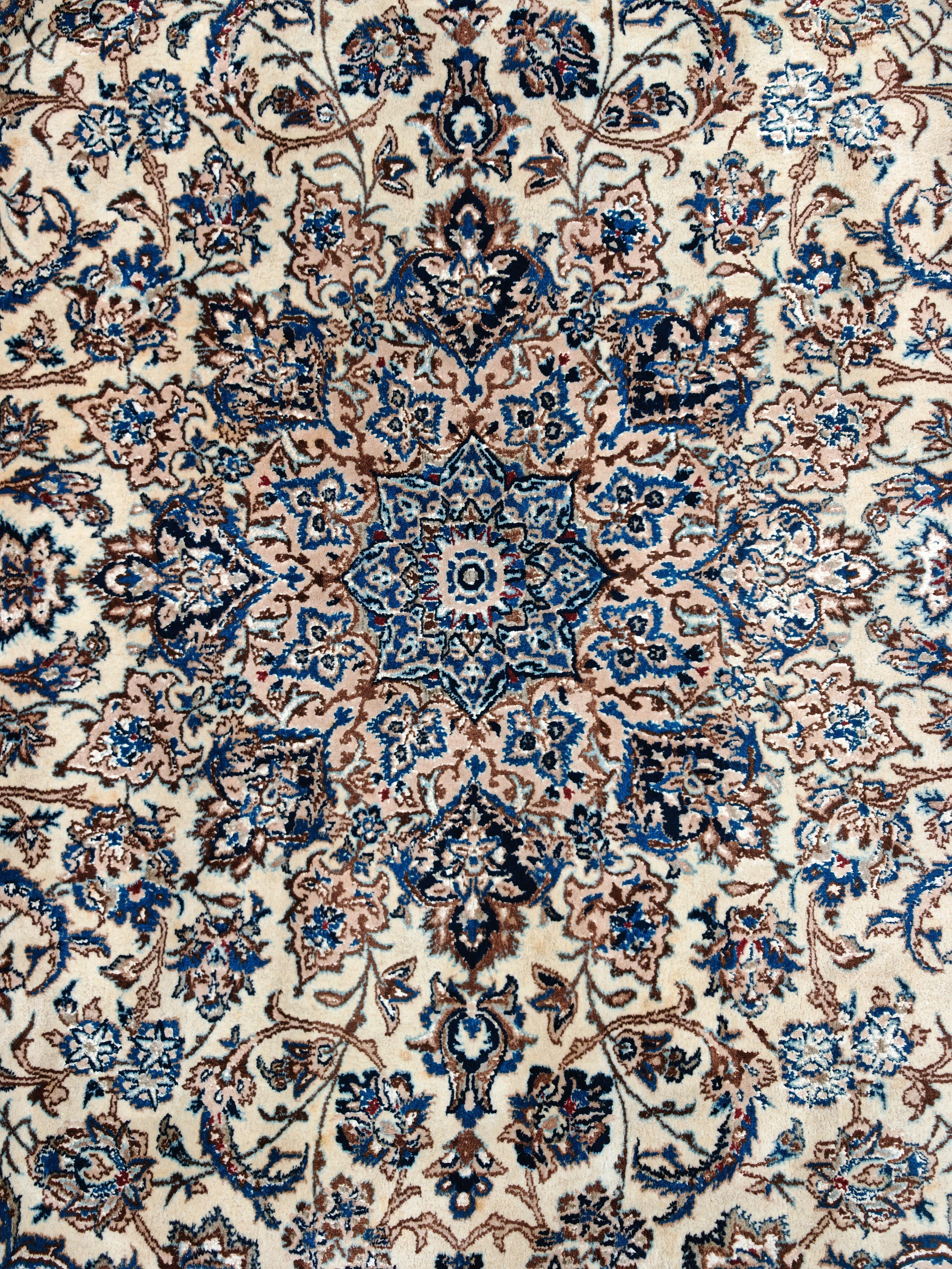 In this listing you will find a stunning vintage hand-knotted Persian Nain rug, known for its high knot density and use of a delicate color palette including ivory, blue, and beige. It is typically made with a combination of wool and silk, providing