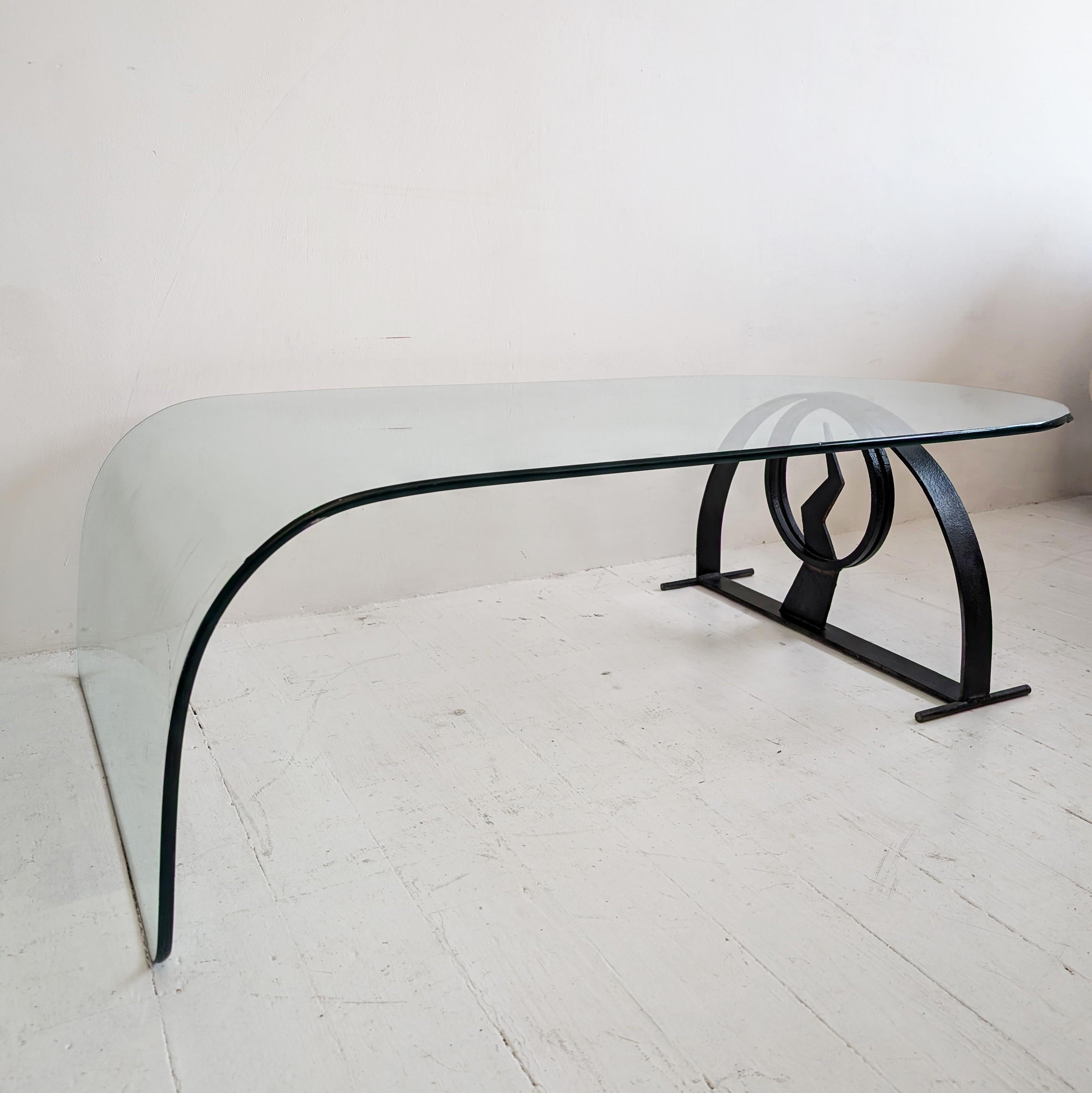 Une étonnante table basse postmoderne en verre incurvé, sur une base en fer noir qui a la forme d'un éclair. En bon état général - comme le montrent les photos, il y a quelques rayures et usures liées à l'âge à la surface et un petit éclat de puce