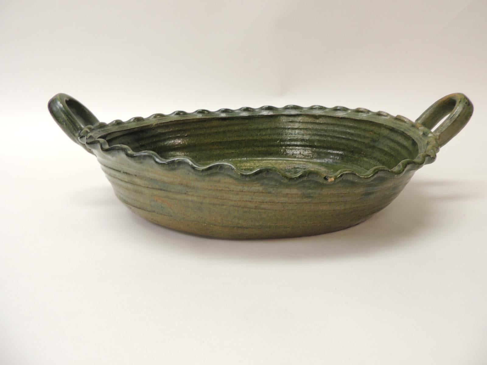 Large vintage Provincial green glazed terracotta oval serving bowl.
Oval earthenware serving bowl with handle and a large blooming flower in the centre of the dish.
Size: 15 x 10 x 3 H.
