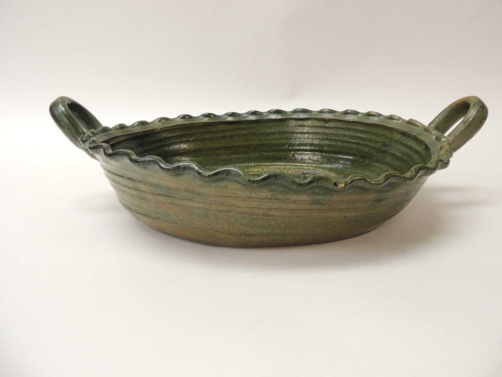 Grand bol de service ovale provincial vintage en terre cuite émaillée verte. 
Bol de service ovale en faïence avec poignée et une grande fleur épanouie au centre du plat. 
Taille : 15 x 10 x 3 H.