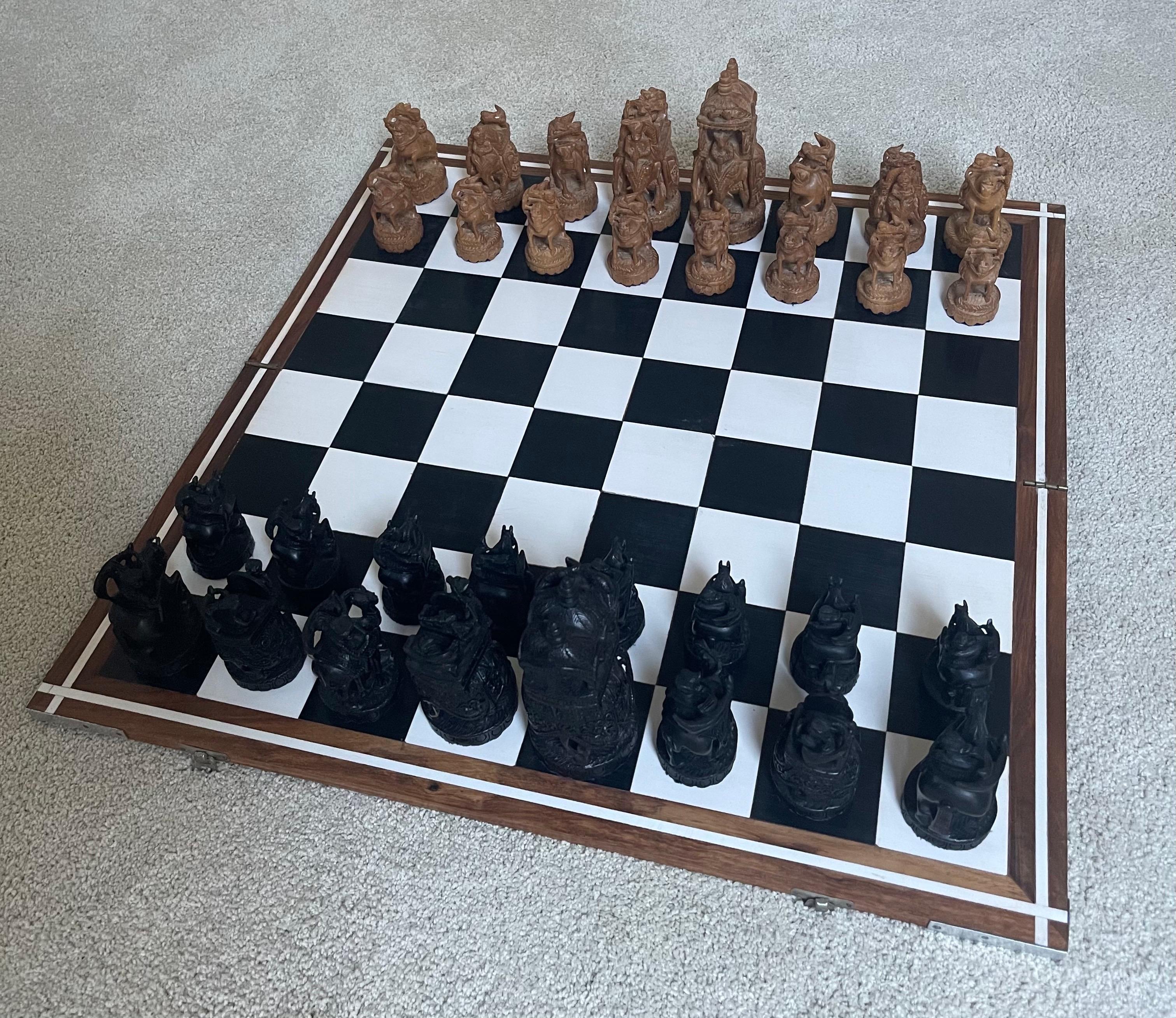 Large hand carved vintage Rajasthani / Indian chess set with foldable wooden board, circa 1960s. The chess pieces are made of what I believe to be resin (although they really look like wood) and are intricately hand carved with amazing detail; they