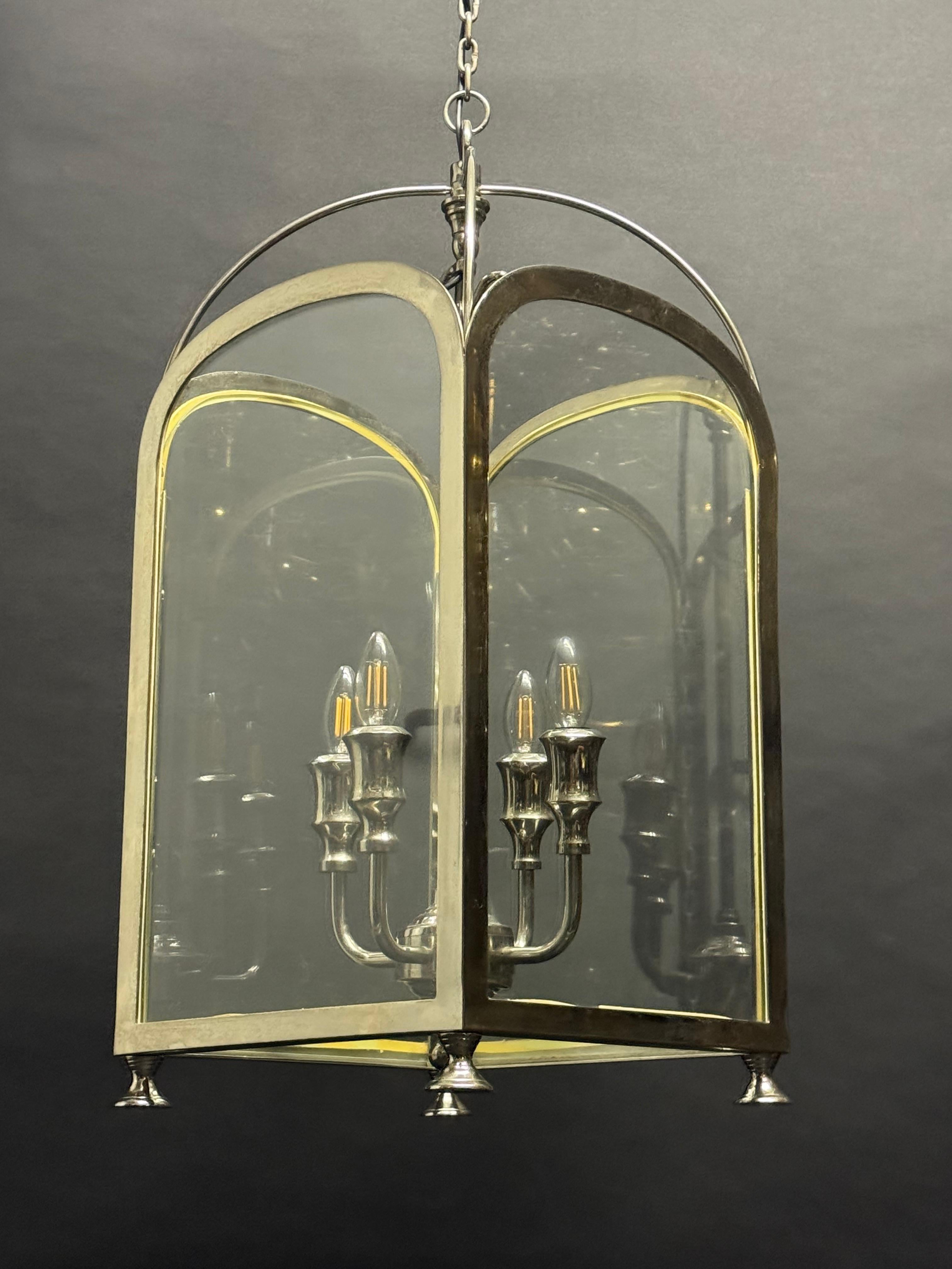 Elegante lanterne de salle suspendue du milieu du 20e siècle avec un haut corps en verre rectangulaire et un sommet arqué. Le cadre est fabriqué en laiton partiellement nickelé combiné à des éléments en acier/fer, conservant sa patine d'origine