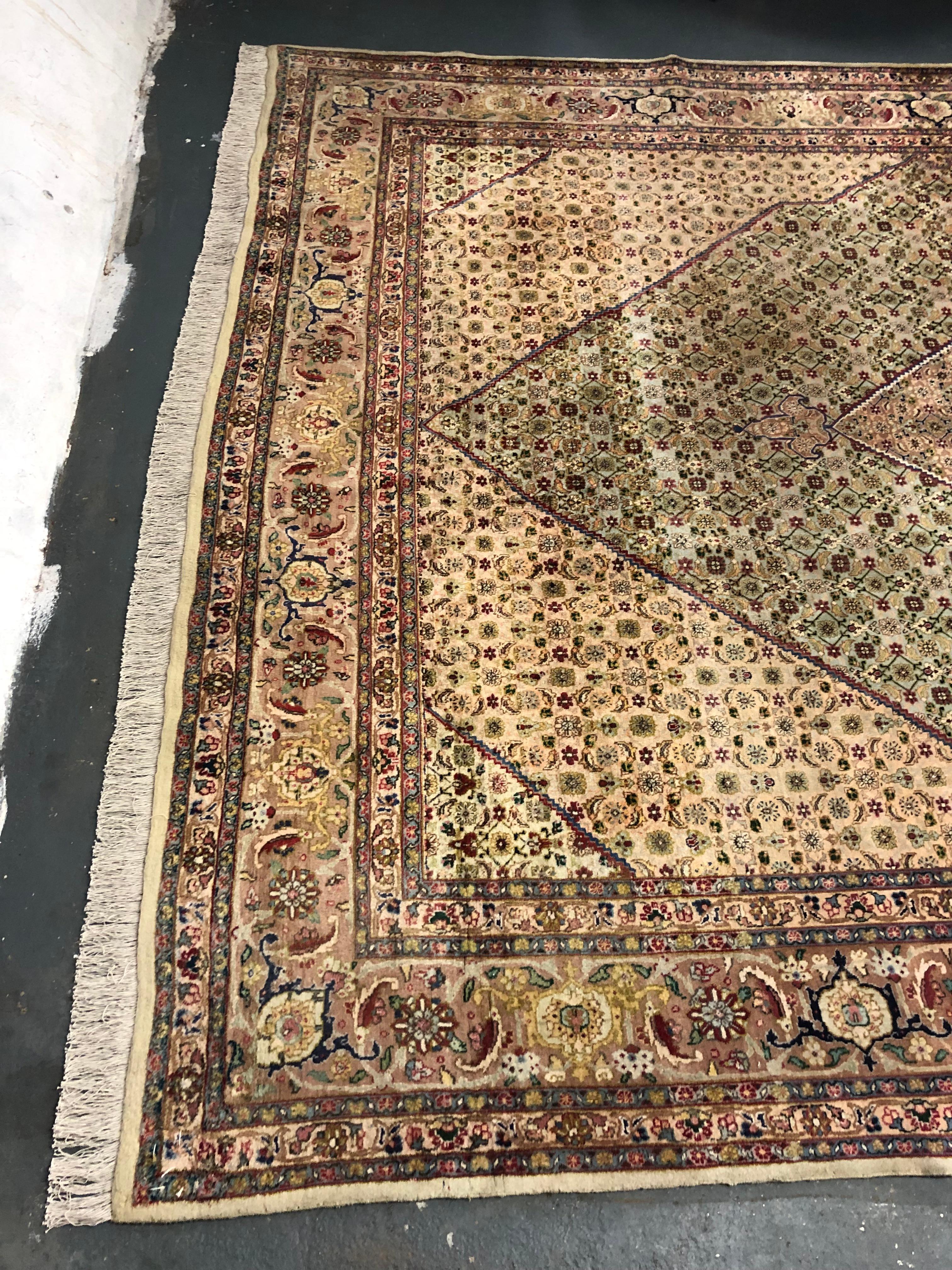 Il design presenta un audace motivo botanico, con un medaglione centrale intrecciato simmetricamente con accenti di baige, rosso, marrone, verde e crema su un semplice sfondo beige. L'intricatezza del disegno persiano Ardebil e l'elegante palette di