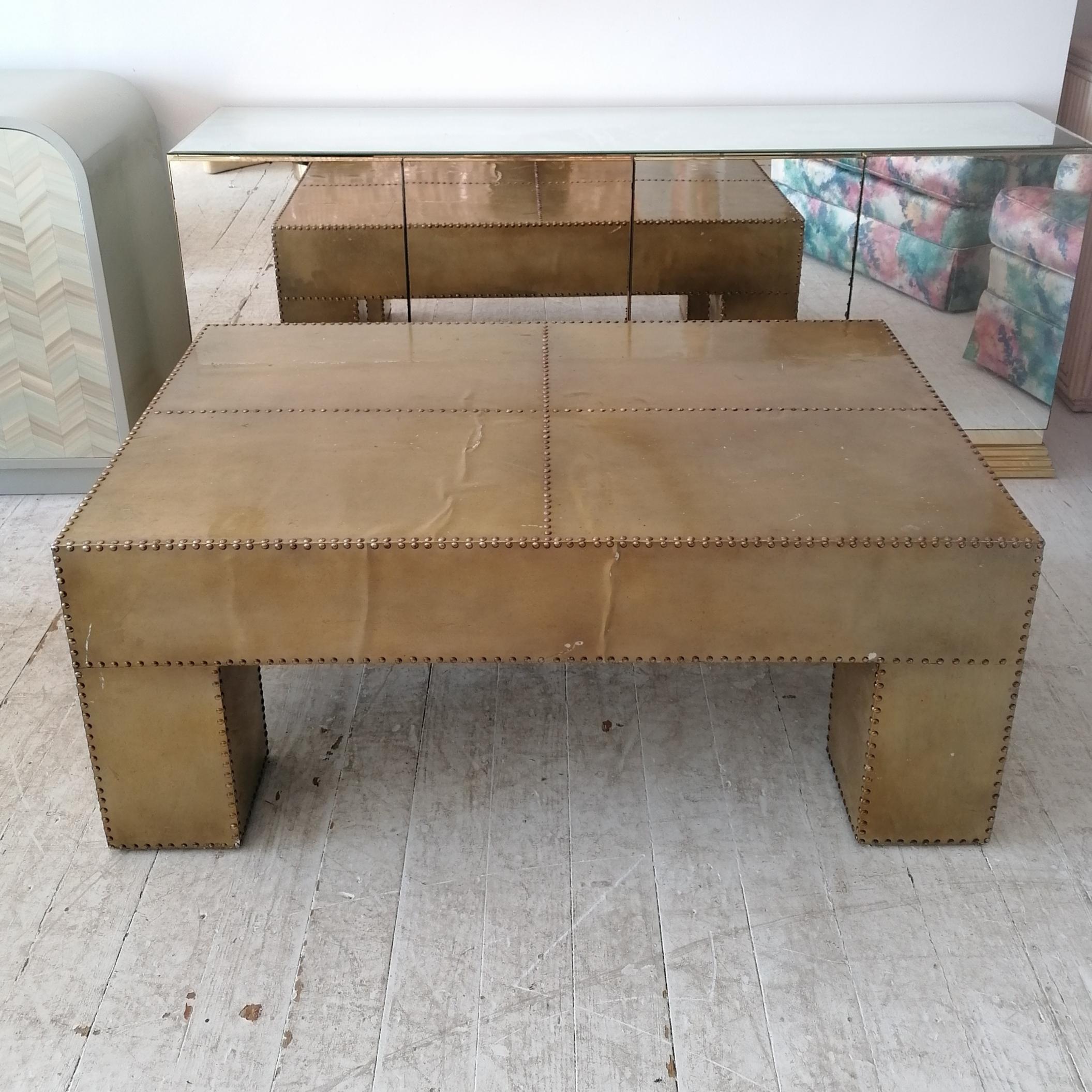 Large Sarreid style coffee table. Clad in brass-coloured aluminium (or possibly nickel?), studded along edges. There's some age-related wear to the brass finish where the aluminium shows through.

Dimensions: width 120.5cm, depth 71cm, height 49.5cm