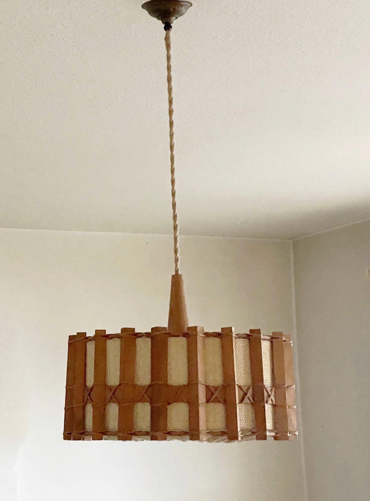 Rare 1960s Scandinavian wooden and woven rattan pendant lamp with textile shade and a single Edison light socket for a large sized screw bulb.
Measures: Diameter 16.50