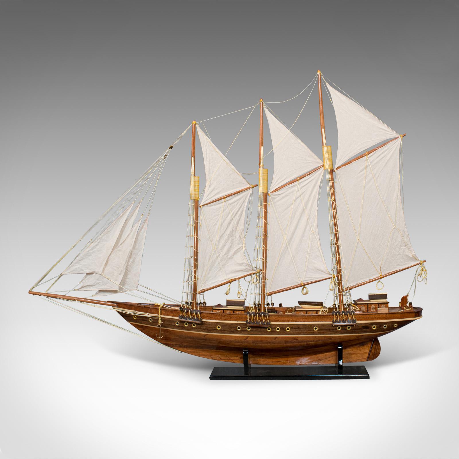 This is a large vintage model of a Classic schooner. An English, mahogany collectible or decorative yacht with display stand and dating to the 20th century.

The schooner is a type of yacht defined by its sail configuration, mostly featuring two