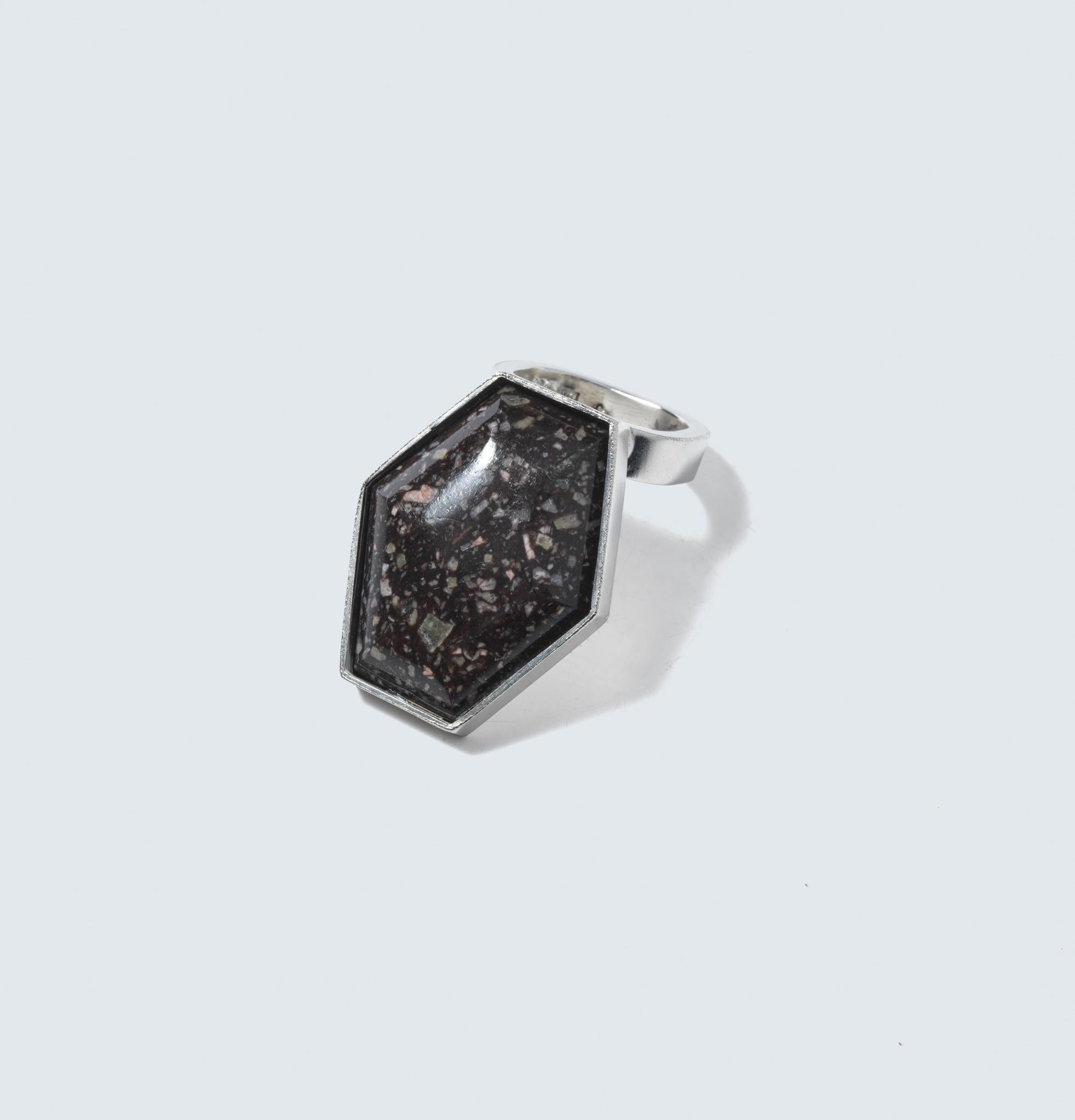 Dieser prächtige Ring verkörpert die Essenz von Forsbergs Handwerkskunst, indem er Sterlingsilber mit dem erdigen Charme des Porphyrs zu einem wahrhaft einzigartigen und fesselnden Schmuckstück verbindet. Der Ring besteht aus einem breiten, flachen