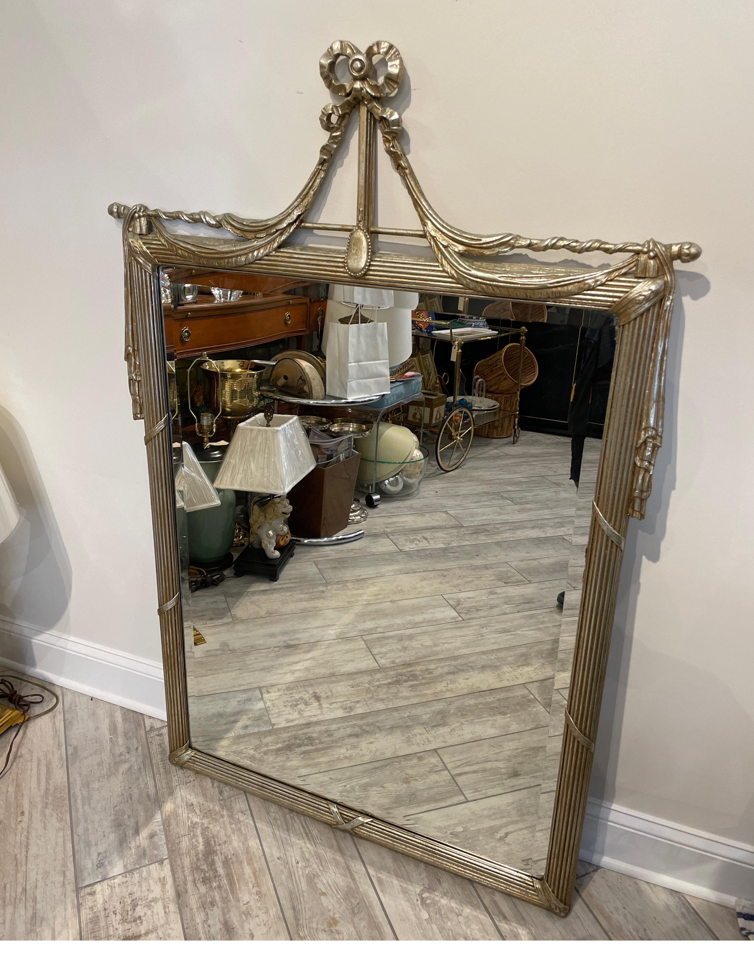 Large silver gilded carved mirror in the swag & ribbon motif. This vintage mirror in the Hollywood Regency style will add glamour to any room.