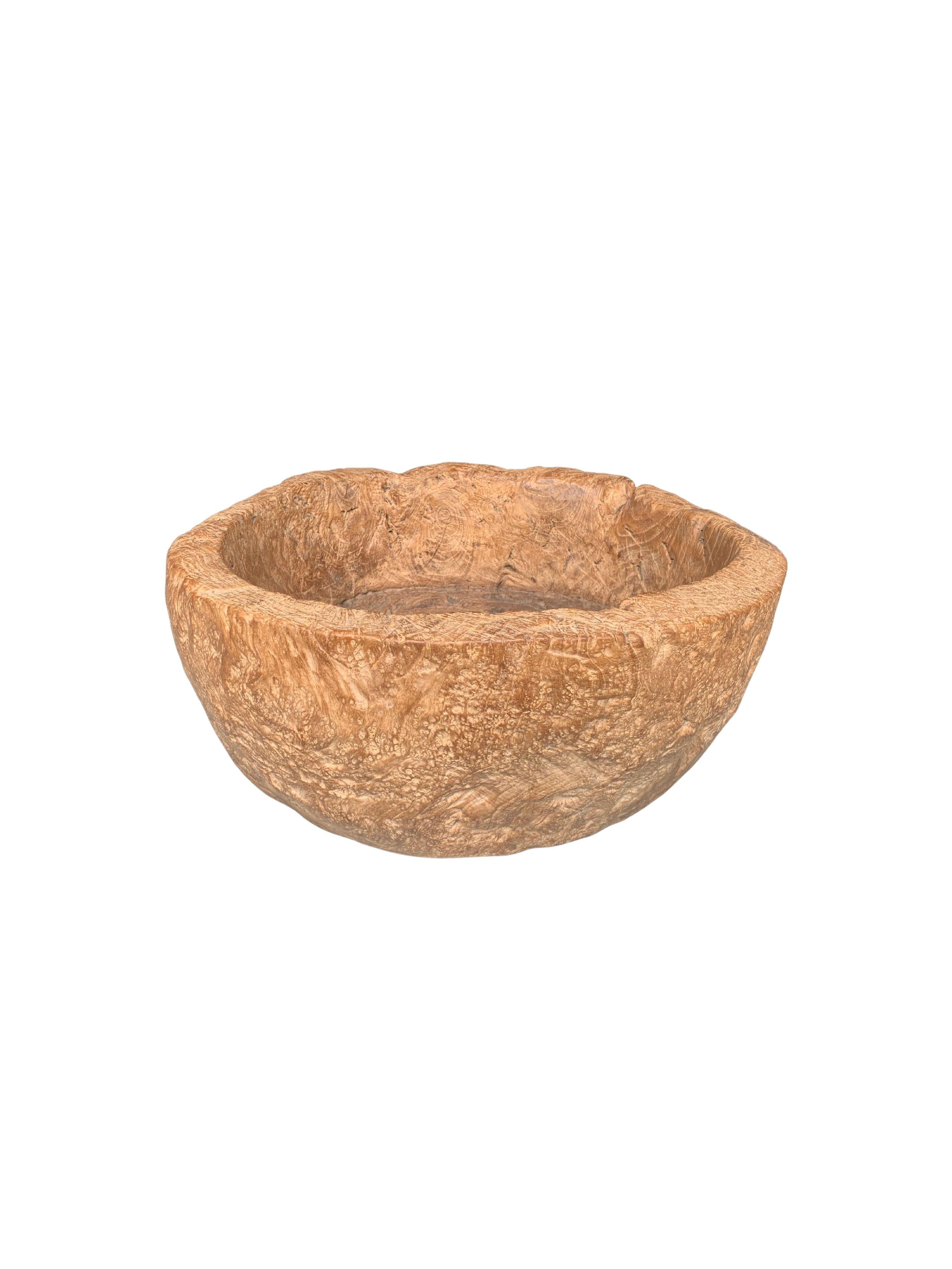 A solid teak wood bowl crafted on the island of Java from a slad of burl wood. The bowl features polished finish and is very solid with a think basin and walls. The bowl was cut from a much larger slab of wood and maintains a minimalist organic