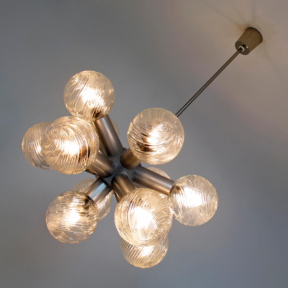 Impresionante gran araña Sputnik de 11 brazos de los años 60 / 70.
El armazón de la lámpara colgante tiene una sección central en forma de estrella con once brazos cilíndricos, cada uno con un globo de cristal con estructura arremolinada.
Esta
