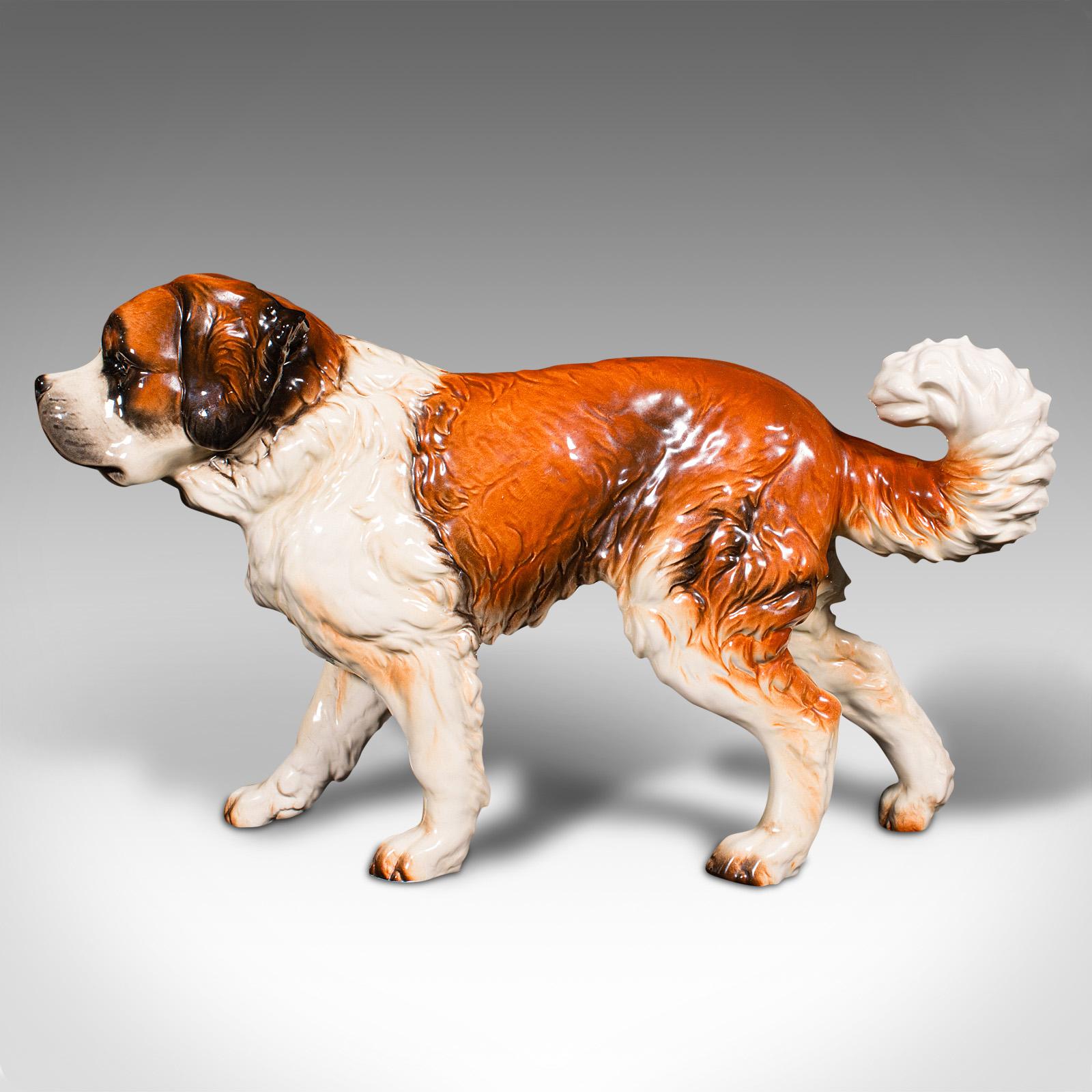 This is a large vintage St Bernard figure. A German, ceramic ornamental dog statue, dating to the late 20th century, circa 1980.

Utterly endearing ornamental study of the famous breed
Displays a desirable aged patina and in very good