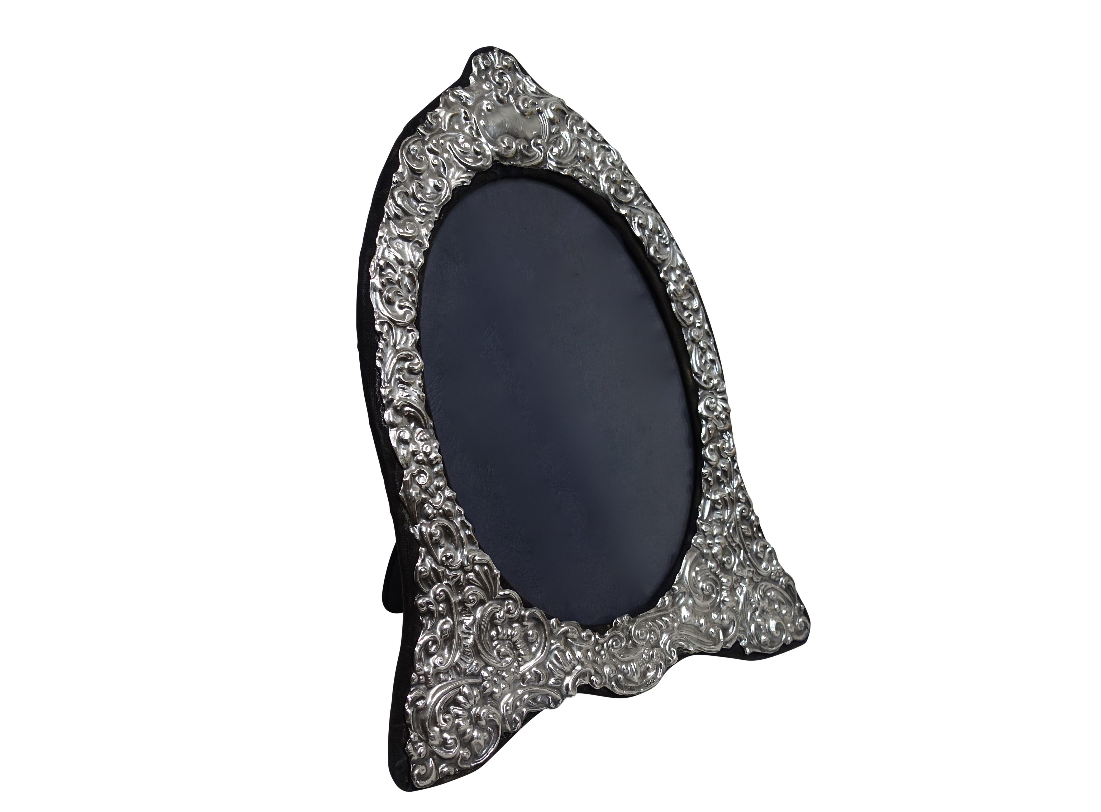 A large repousse sterling silver tabletop picture frame with blue velvet easel back. Fully hallmarked along the bottom edge, London England and made by the Key Ford Frames LTD.
The inner sight of this frame measures 8.5 inches high x 6 inches wide.