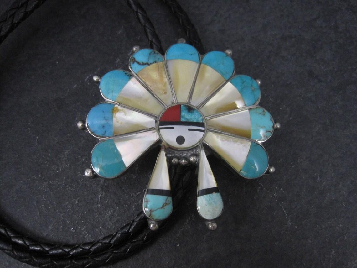 This gorgeous vintage sunface bolo is sterling silver with turquoise, mother of pearl, coral and jet inlay.

Measurements: 2 3/8 by 2 3/8 inches

Marks: None

Condition: Excellent

Comes with a new 36 inch leather tie.
