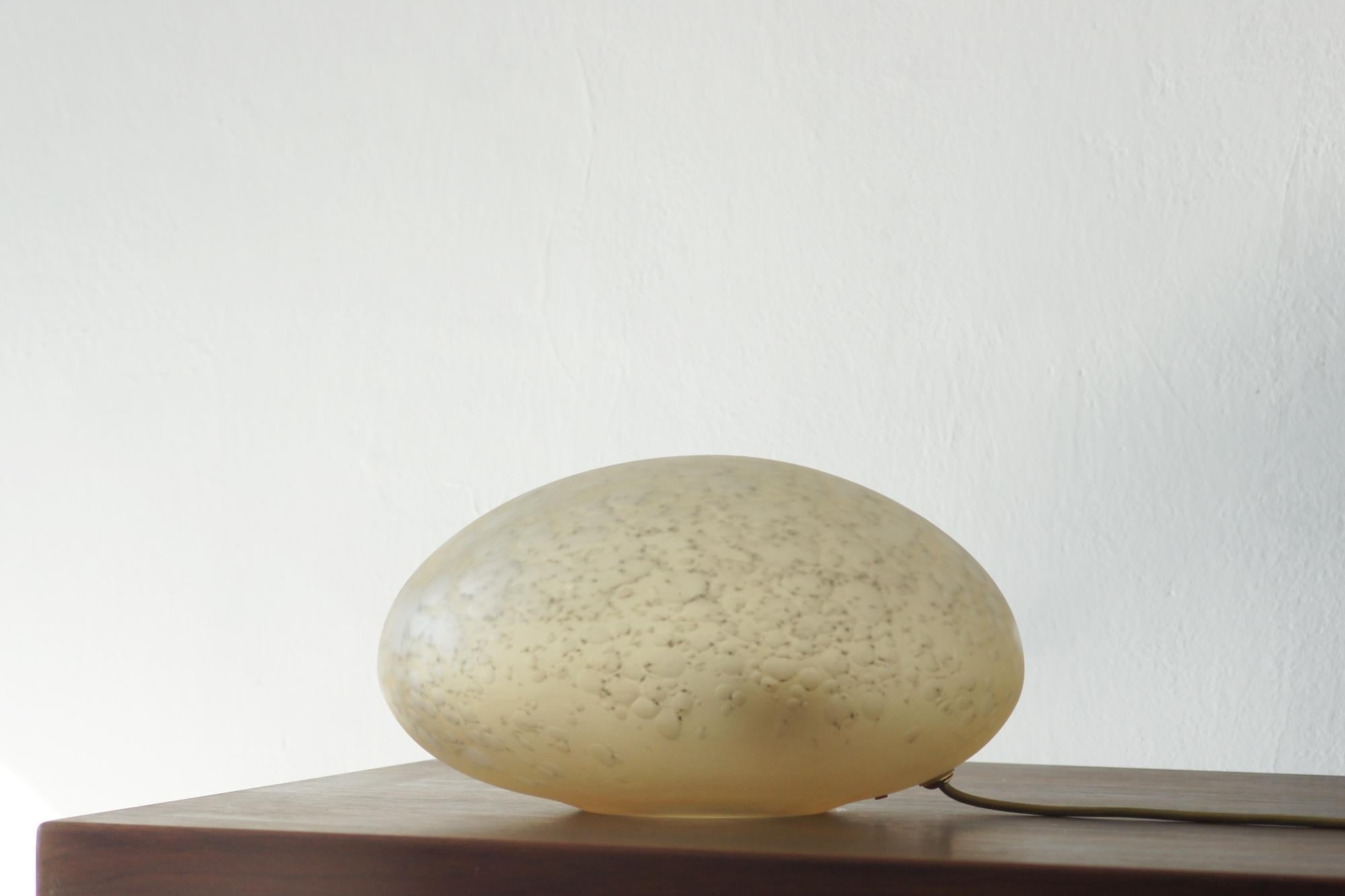 Une lampe de table unique de La Murrina, réalisée en verre artistique de Murano dans des tons de beige mat avec des reflets dorés. De minuscules bulles d'air sont visibles dans la structure du verre, ce qui confère à la forme un caractère organique,