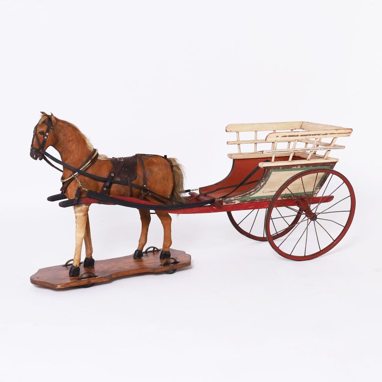 Impressive hand crafted toy horse and cart with a realistic cowhide cover horse with authentic tack on a wood platform with wheels. The hand painted cart has wooden wheels with metal spokes and rims.