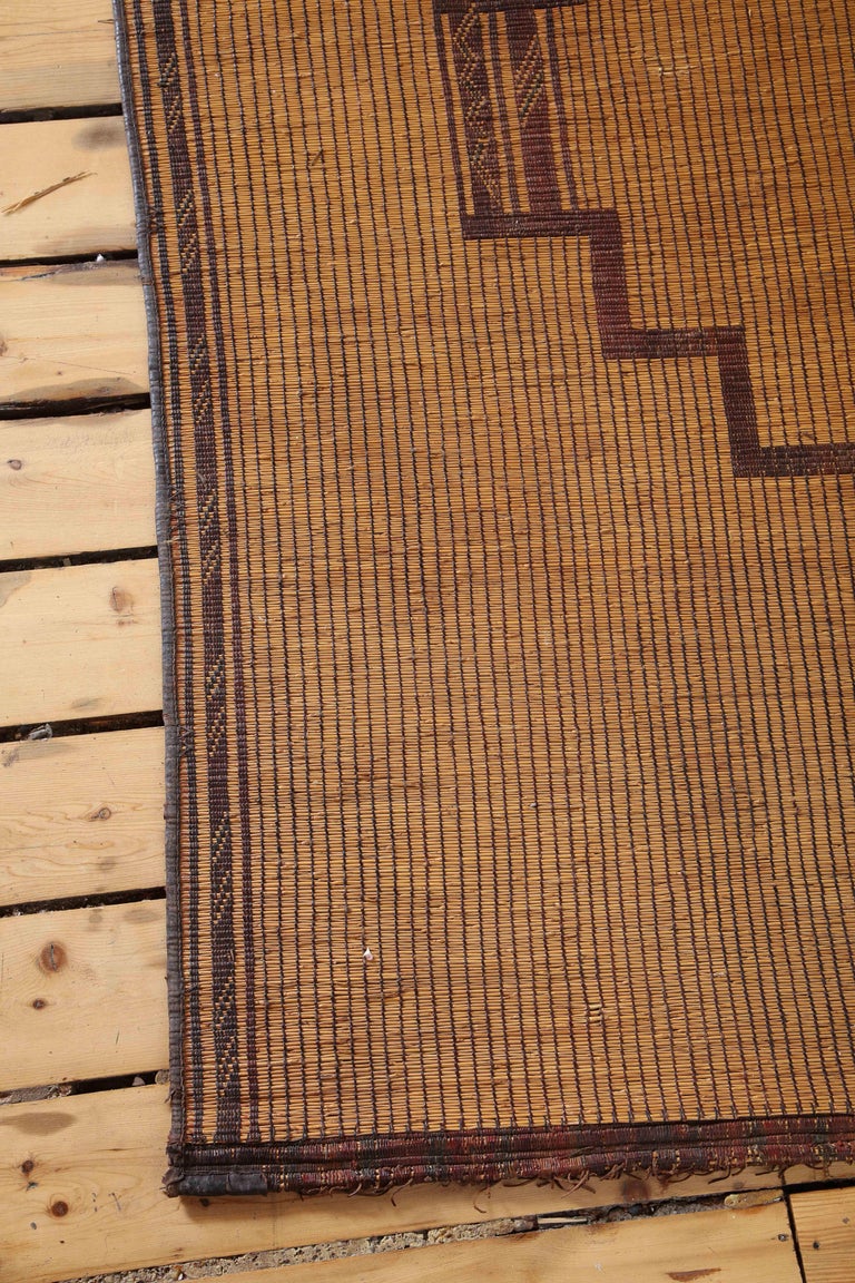 A midcentury tribal rug or mat handwoven by the Tuareg tribes in Mauritania of reed bound with leather. As such, it has all the 