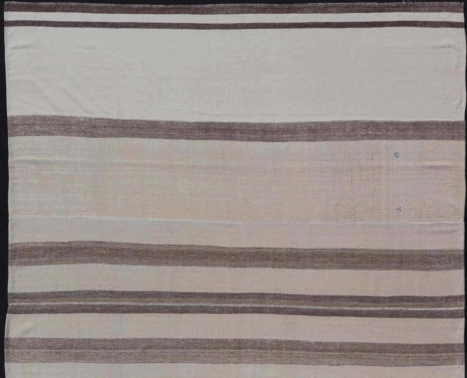 Flat-weave Kilim vintage rug from Turkey with stripes in brown, white, taupe, and cream Rug TU-NED-1003, country of origin / type: Turkey / Kilim, circa 1940.

Woven during the mid-20th century in Turkey, this multi paneled Kilim is decorated with a
