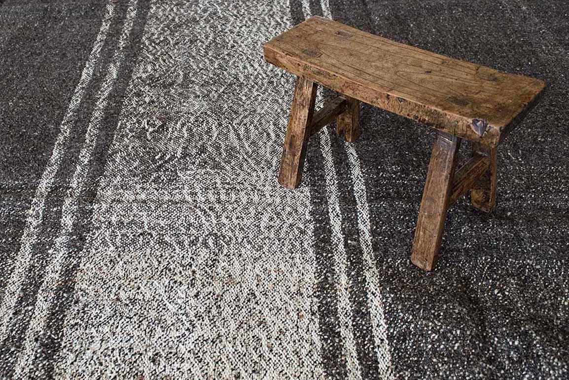 This large vintage Kilim from Anatolia in dark brown has a vertical line that runs along the entire piece. The optical effect would work beautifully in any decor and the natural patina brings an organic quality to any design aesthetic. 

This