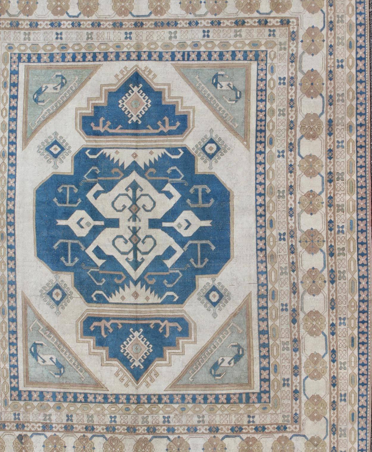 Large vintage Turkish rug with stylized geometric design in blue, ivory, tan. Keivan Woven Arts / rug 16-0914, country of origin / type: Turkey / Oushak, circa 1950
Measures: 13' x 15'8.
This vintage Turkish Oushak rug features an intricately
