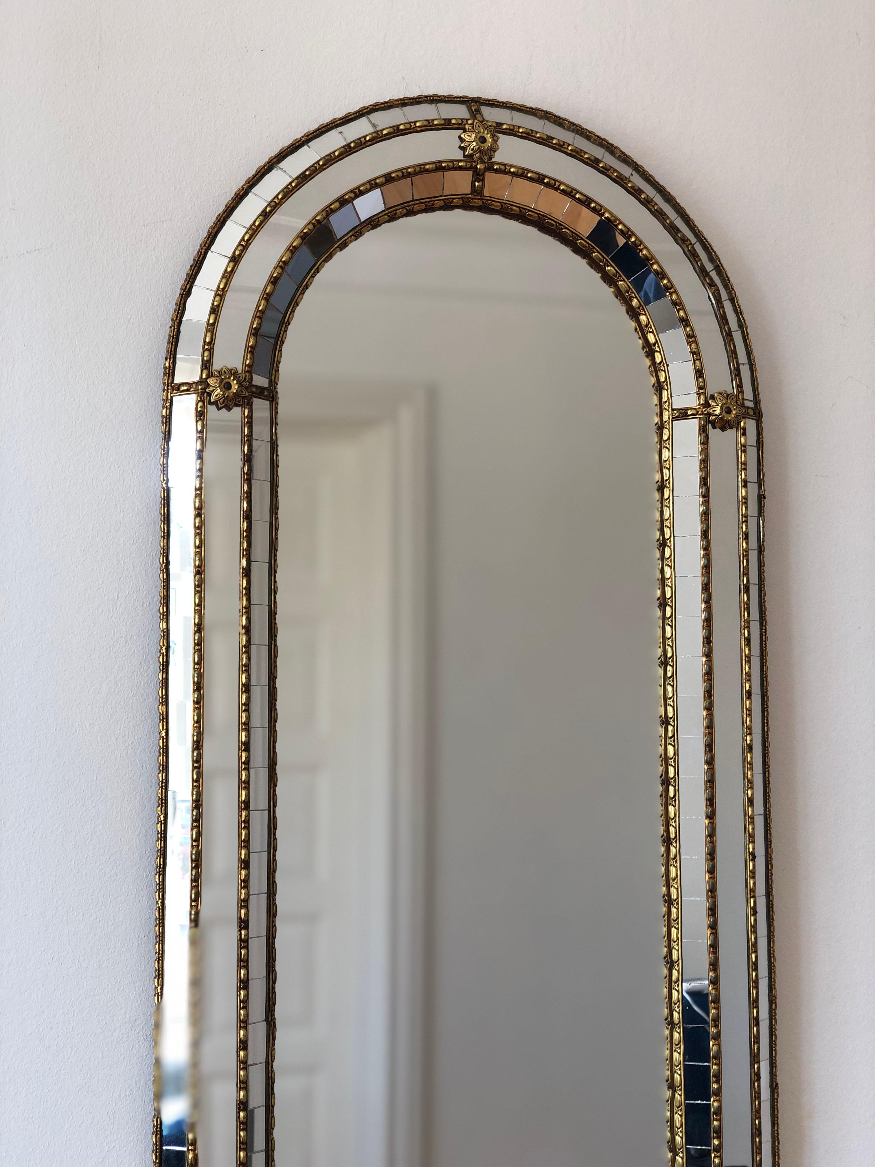 A Vintage Venetian full length mirror in Spanish style, dating back to the 1990s.
The frame is beautifully hand-crafted and decorated with small crystals on the outer and inner edges, with larger crystals running along the center. The elegant brass