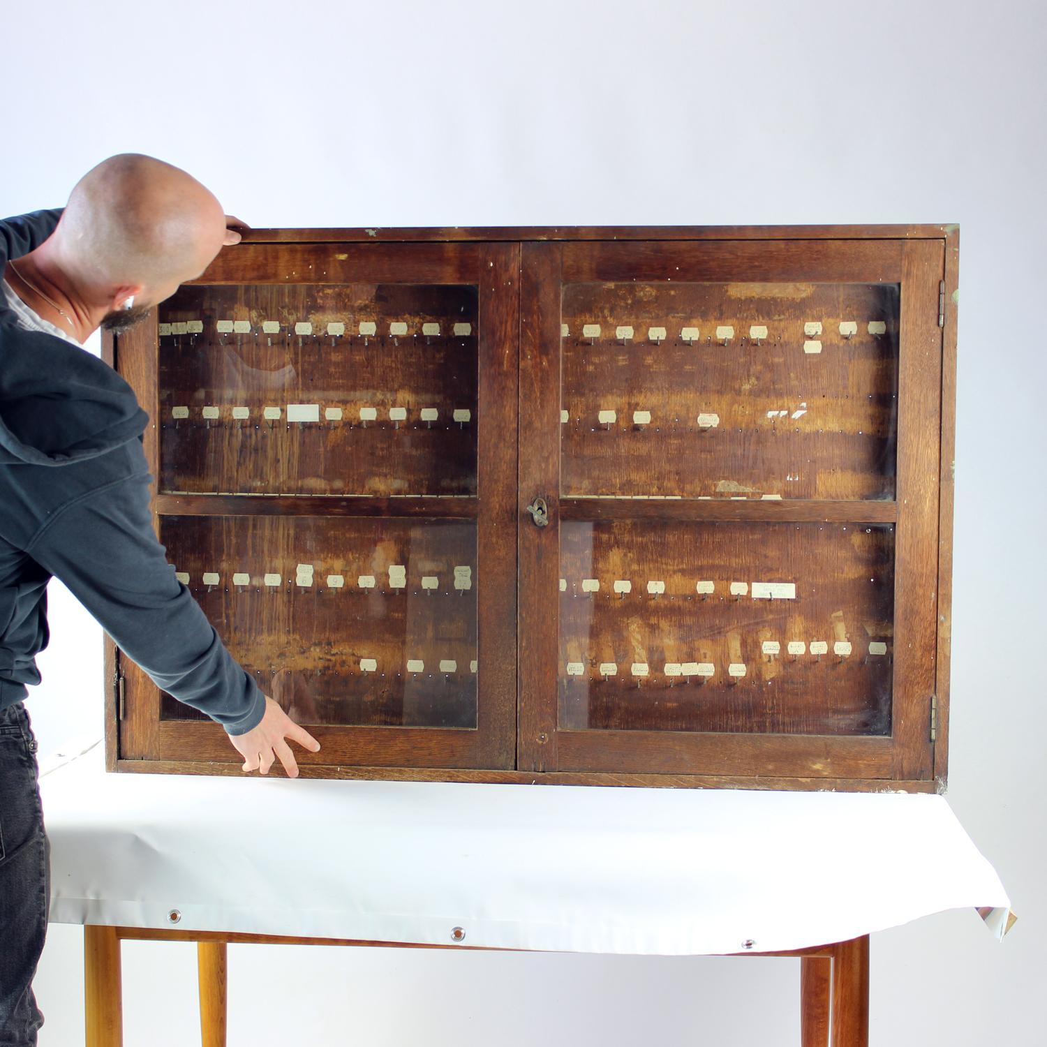 Cette remarquable armoire murale vintage provenant d'une usine tchécoslovaque est un véritable témoignage de l'histoire et du design industriels. Datant des années 1920, l'armoire comporte deux portes vitrées encadrées de bois, révélant un intérieur