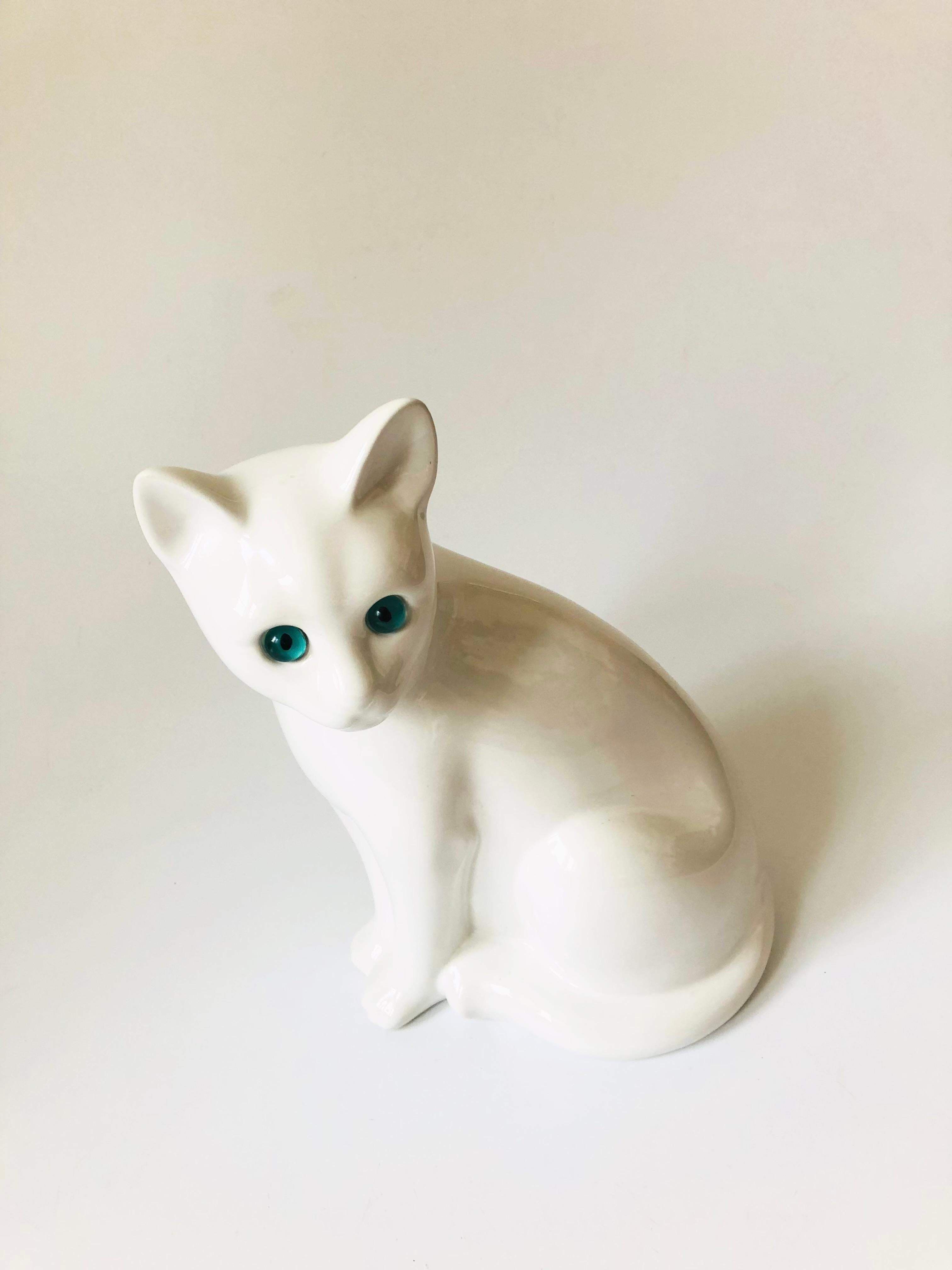 A vintage ceramic cat sculpture finished in a glossy white glaze with blue eyes. Made in Portugal by Elpa Alcobaca, marked on the base.


