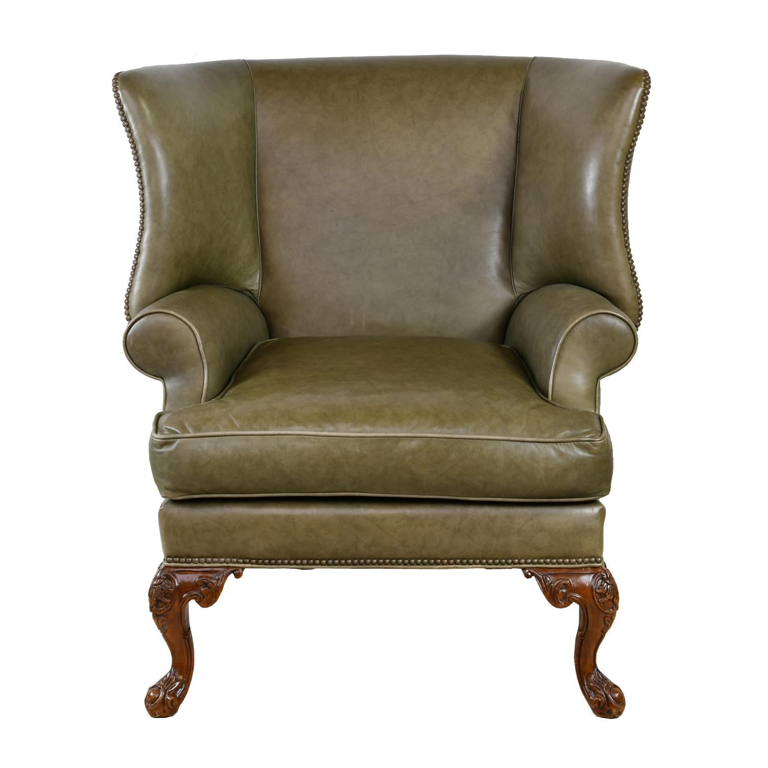 A large and well-proportioned wingback armchair beautifully-upholstered in a high quality sage-green colored leather with decorative nailheads, and resting on carved cabriole feet with splayed back legs. Springform cushion offers added comfort,