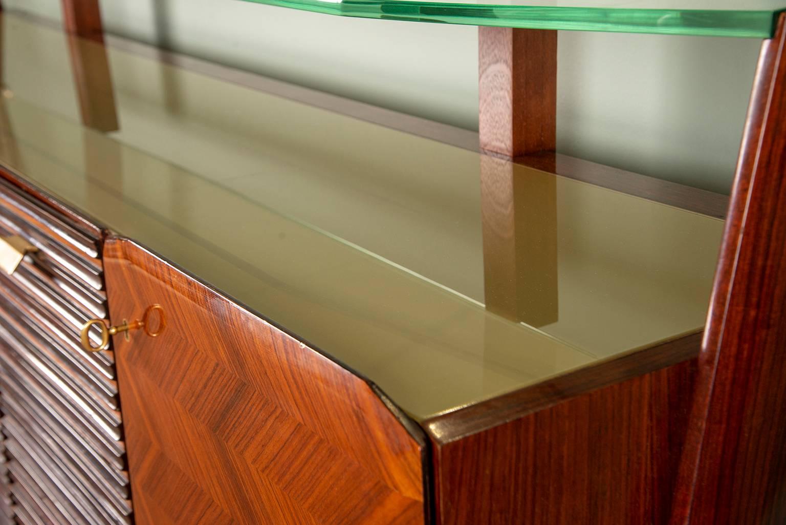 Circa 1950s large Italian sideboard by unknown maker in the style of Vittorio Dassi. Top has floating style glass supported by tops of stylized wishbone form legs at sides, glass insert top, three center hinged cabinets with interior shelves and