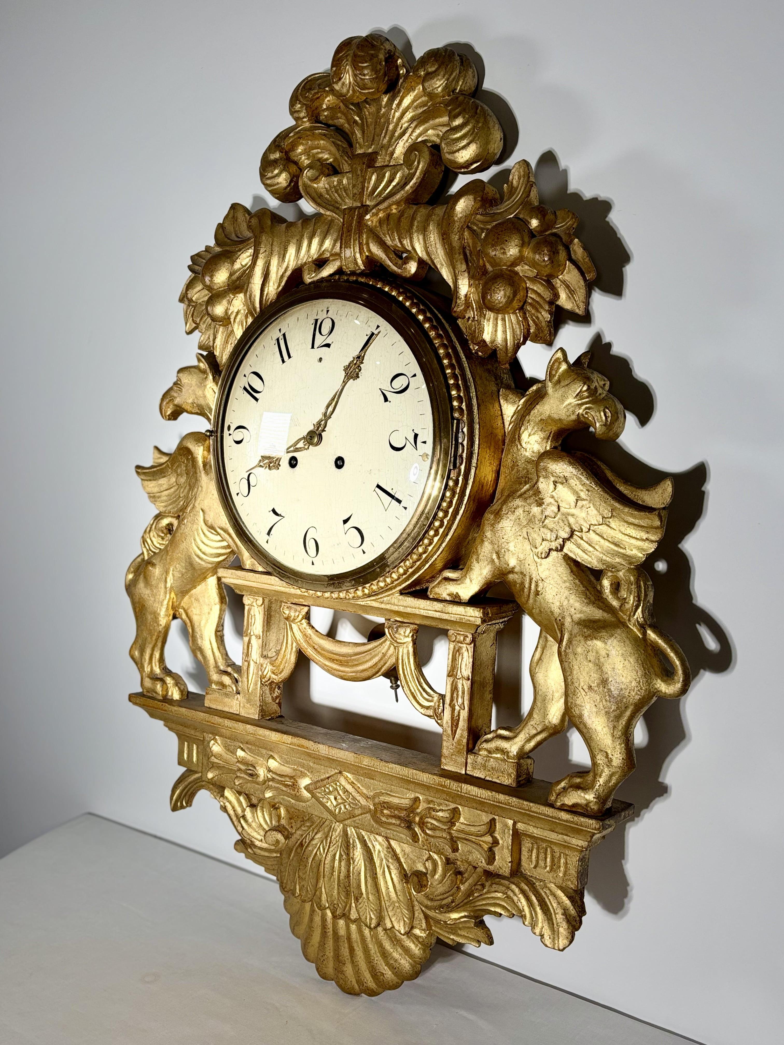 Gran reloj de pared con grifos alados en madera dorada, Suecia, S. XIX Sueco en venta