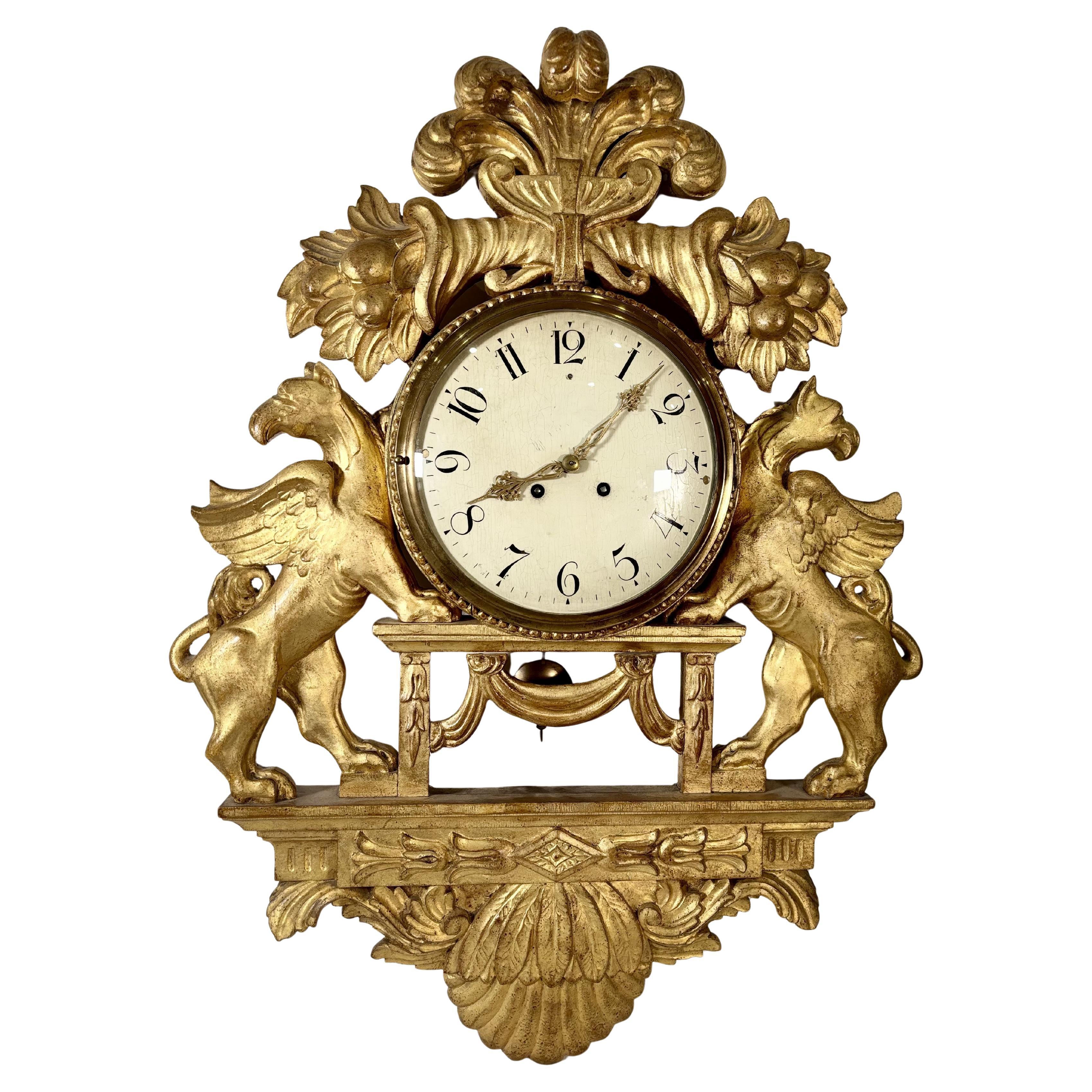 Gran reloj de pared con grifos alados en madera dorada, Suecia, S. XIX en venta
