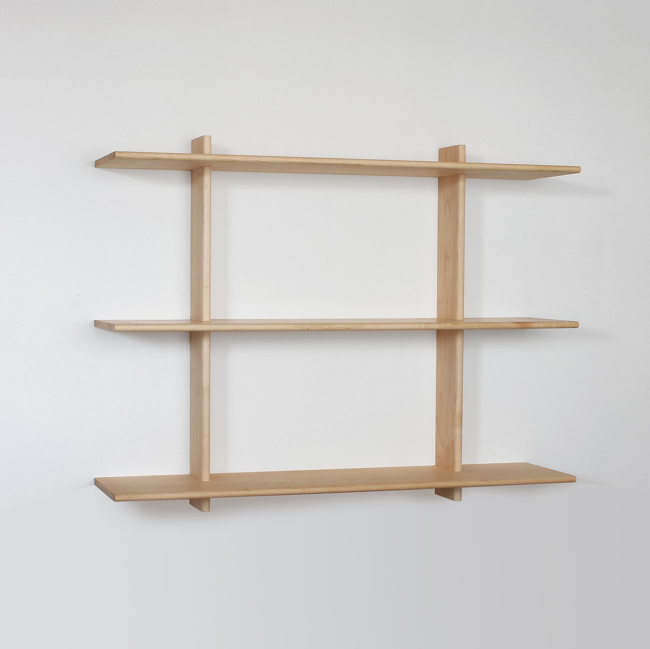 Solid maple shelving unit that hangs from wall and ready to ship. Installation instructions and hardware included. The vertical frames attach to the wall and have slots that precisely hold the deep shelves in place. Rounded edges add visual