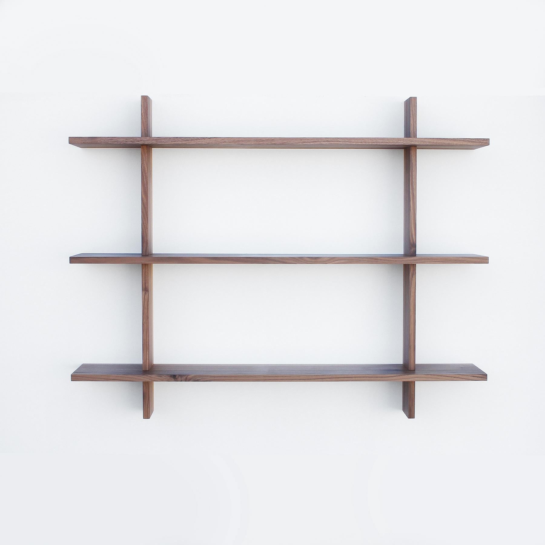 Solid walnut shelving unit that hangs from wall. Hand selected premium hardwood finished in durable natural hard wax/ oil finish. The vertical frames attach to the wall and have slots that precisely hold the shelves in place. All joinery in this