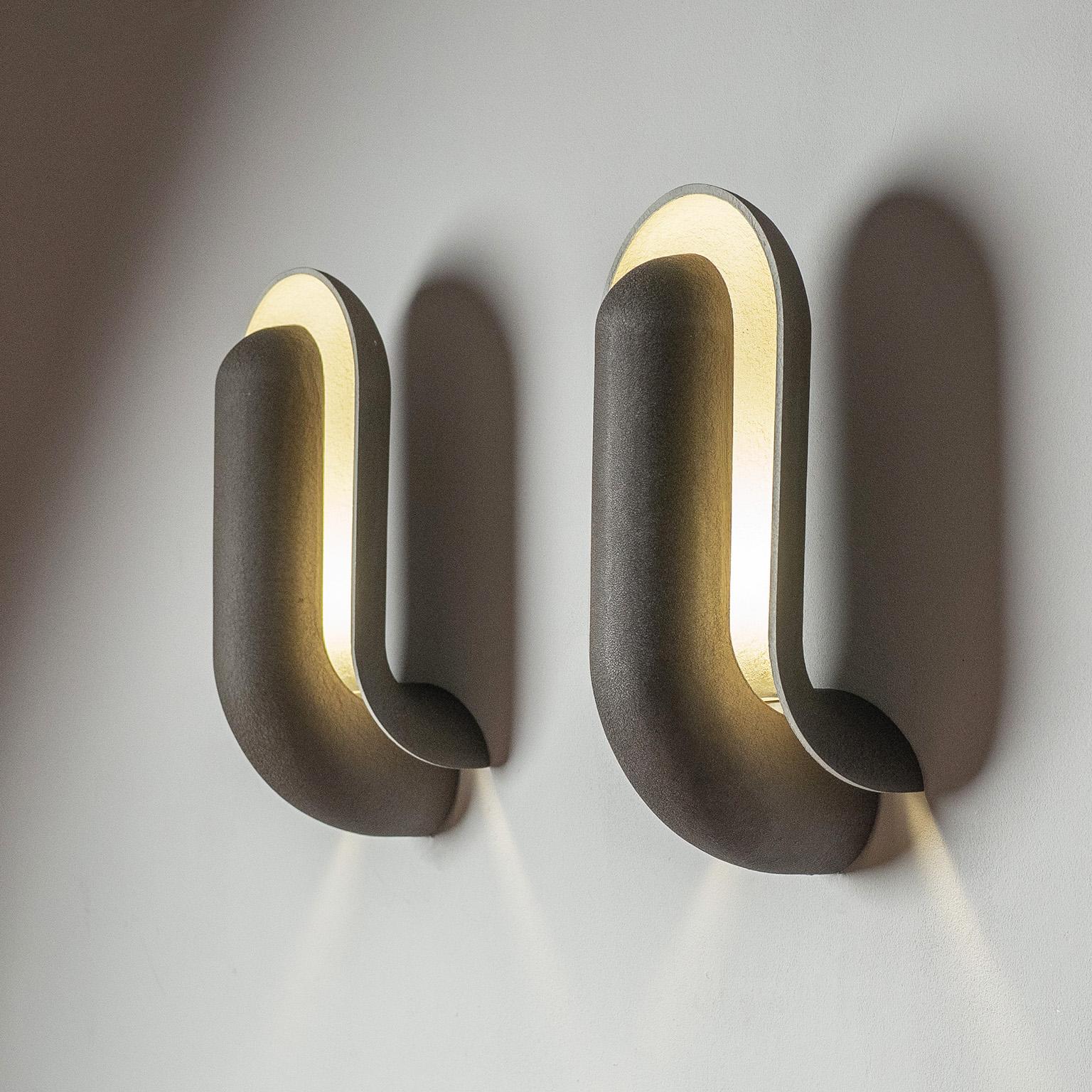Large sconces designed by Piet Cohen for RAAK in the 1970s. Dubbed ‚Schelpdier‘ (Dutch for shellfish) these consist of two overlapping cast aluminum elements for an indirect light. Coated in matte wrinkle paint, brown on the outside and off-white on