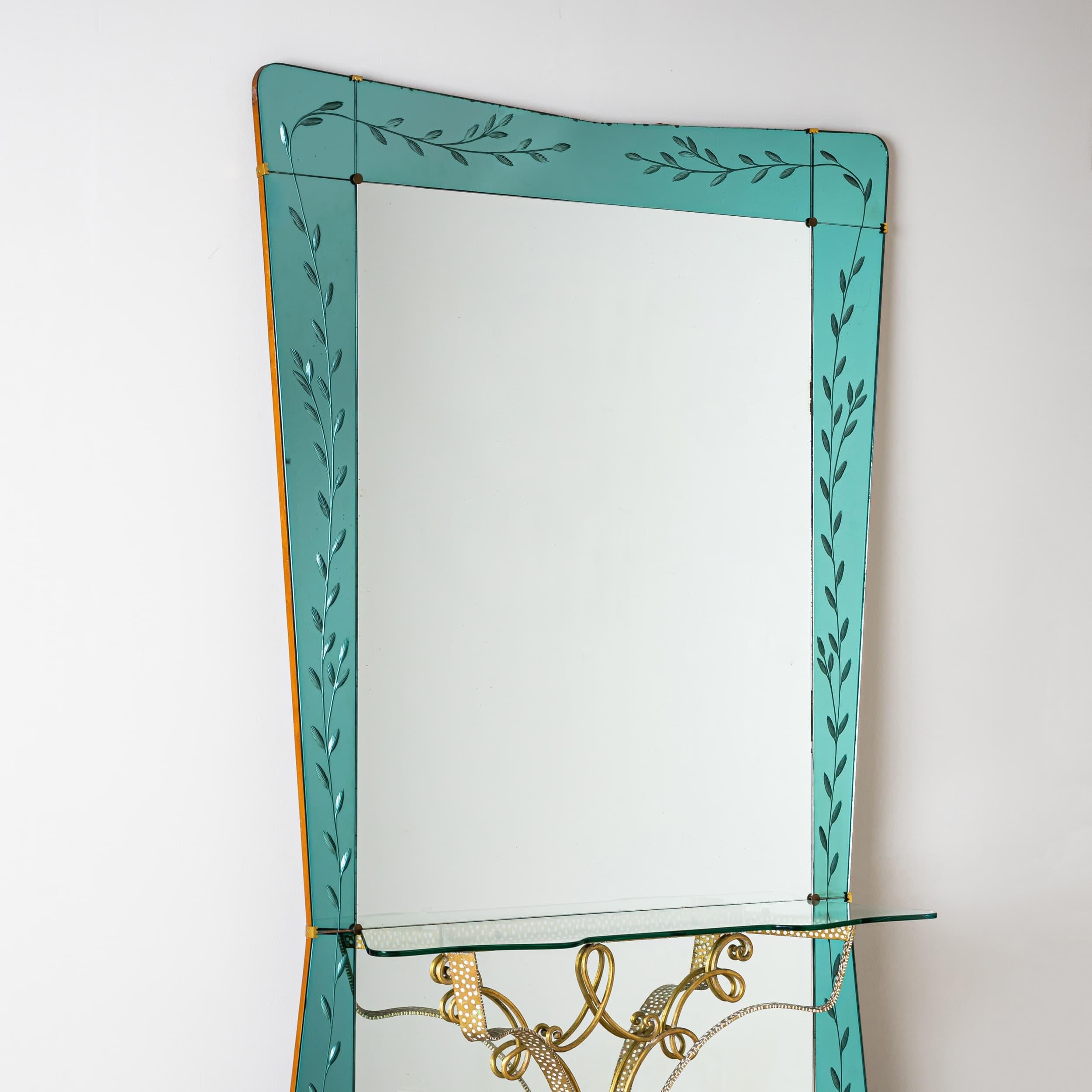 This impressive Italian wall mirror from the 1940s features a double trapezoidal shape and subtle floral etched decor on a bluish background framing the mirror. The accompanying console table is made of brass, complementing the mirror's elegant