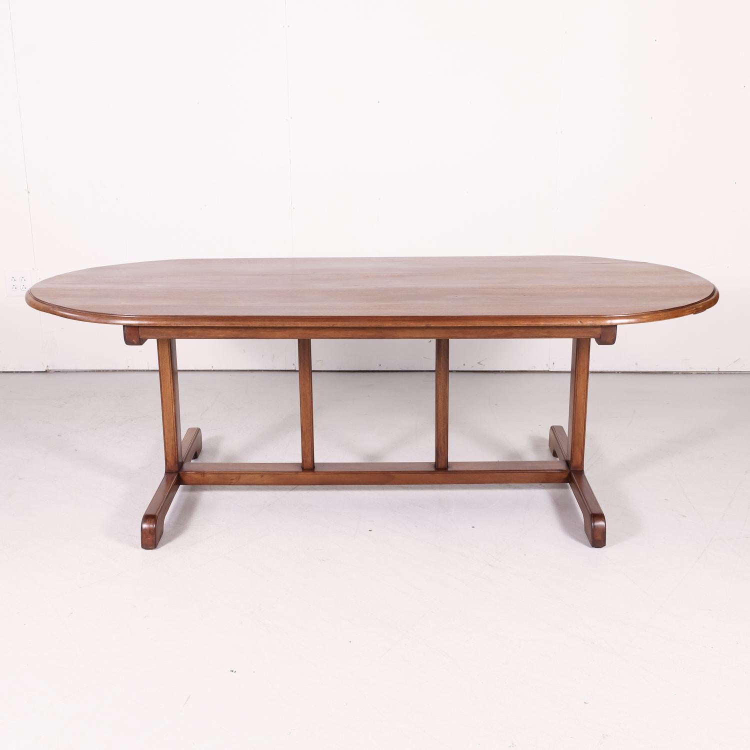 A large 19th century French vendange or wine tasting table handcrafted of solid walnut near Toulouse, having a three plank oval or elliptical shaped top with an ogee edge supported by arched sledge feet joined by a stretcher with center supports,