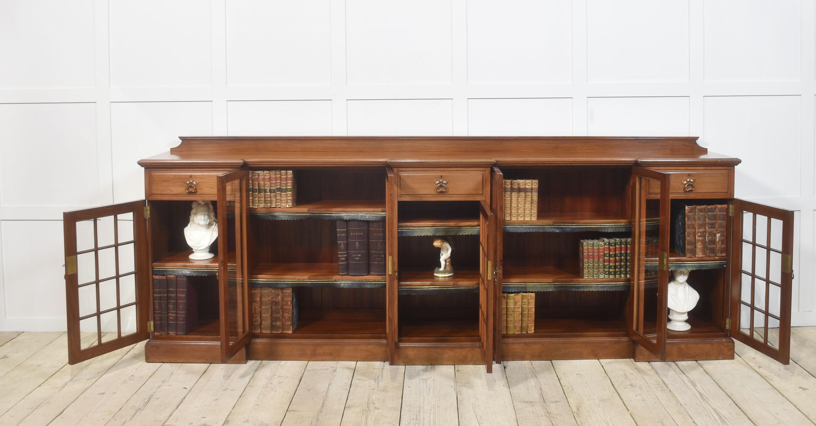 Libreria in noce di tipo Arts and Crafts, con piano rettangolare con schienale a galleria rialzato e tre cassetti a fregio con maniglie stilizzate, sostenuta da una serie di ante vetrate che si aprono per rivelare un interno a ripiani regolabili. Il