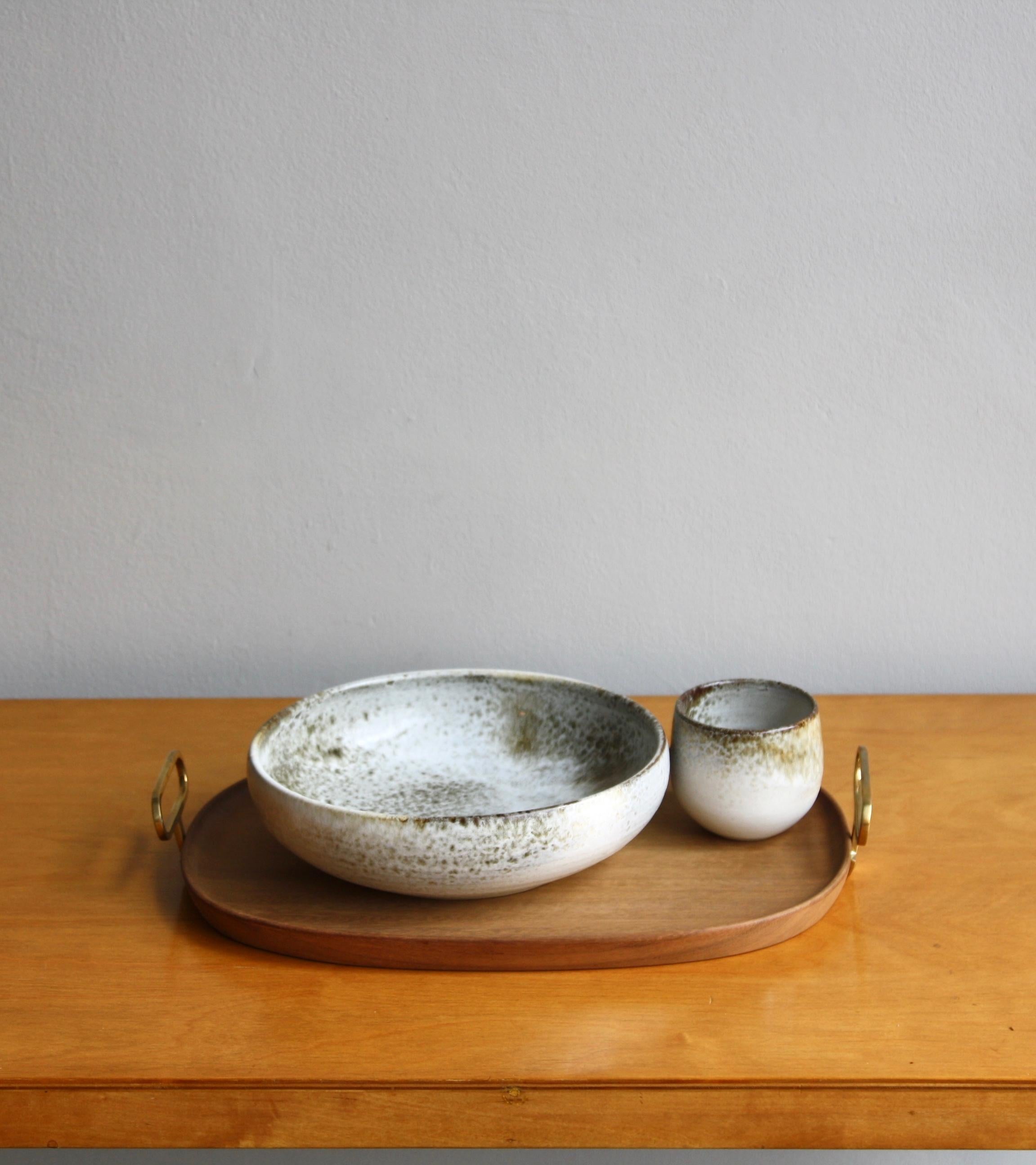 An oblong wooden tray with brass handles designed and made by Carl Auböck II, circa 1950. The large yet minimal tray carved from solid walnut has a rim just 2 mm tall which adds elegance and functionality to the design. Securely screwed to each end