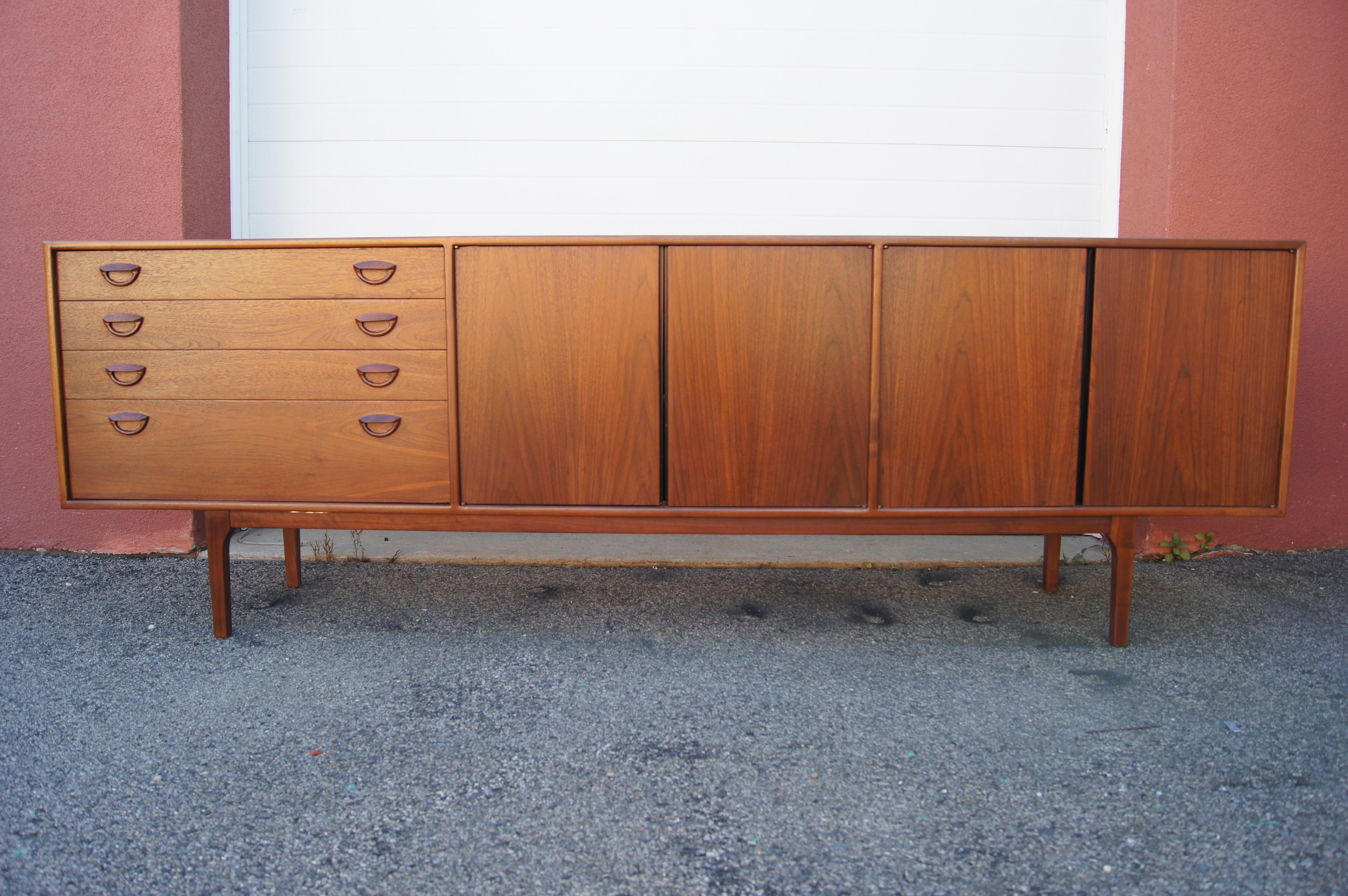 Designed by Kai Kristiansen in the 1960s, this long sideboard exemplifies clean-lined Danish modernism. The walnut case comprises four doors behind which are two sections of adjustable shelves and, to the left, four wide drawers, the topmost of