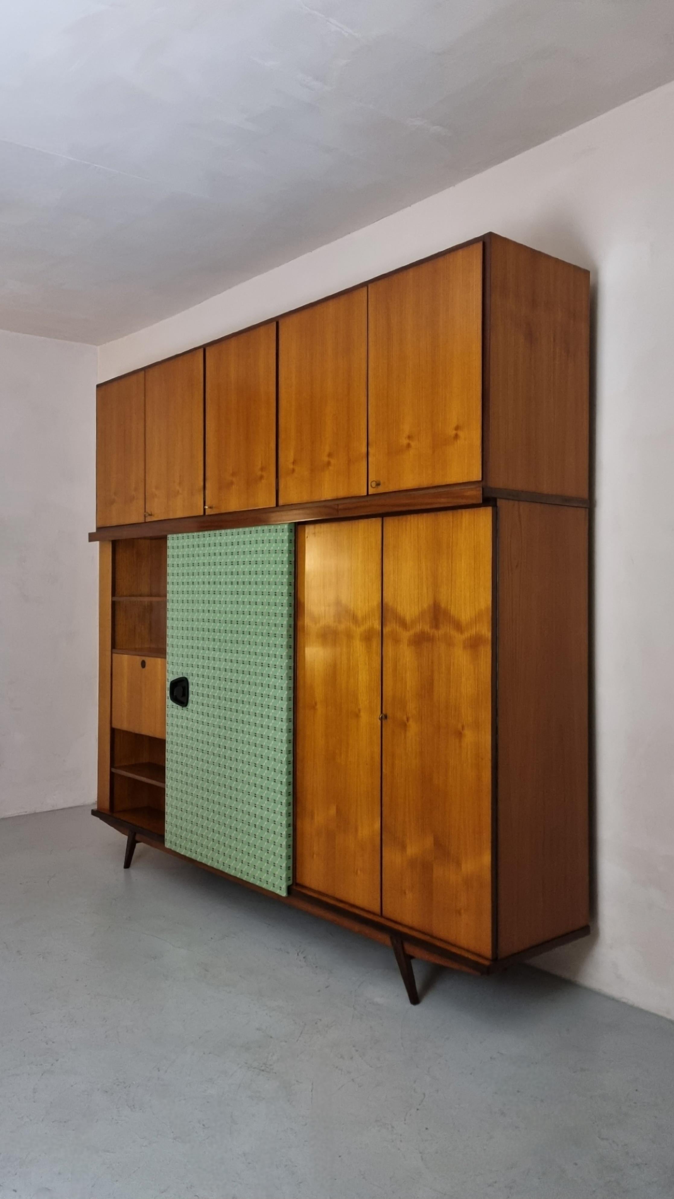 Large wardrobe unit attributed to Gio Ponti  1950s.
Veneered wood structure, brass, mirrored glass, wool fabric, painted metal details.
The wardrobe is composed of 2 overlapping units, sliding door, wardrobe compartment, clothes hanger, mirror,