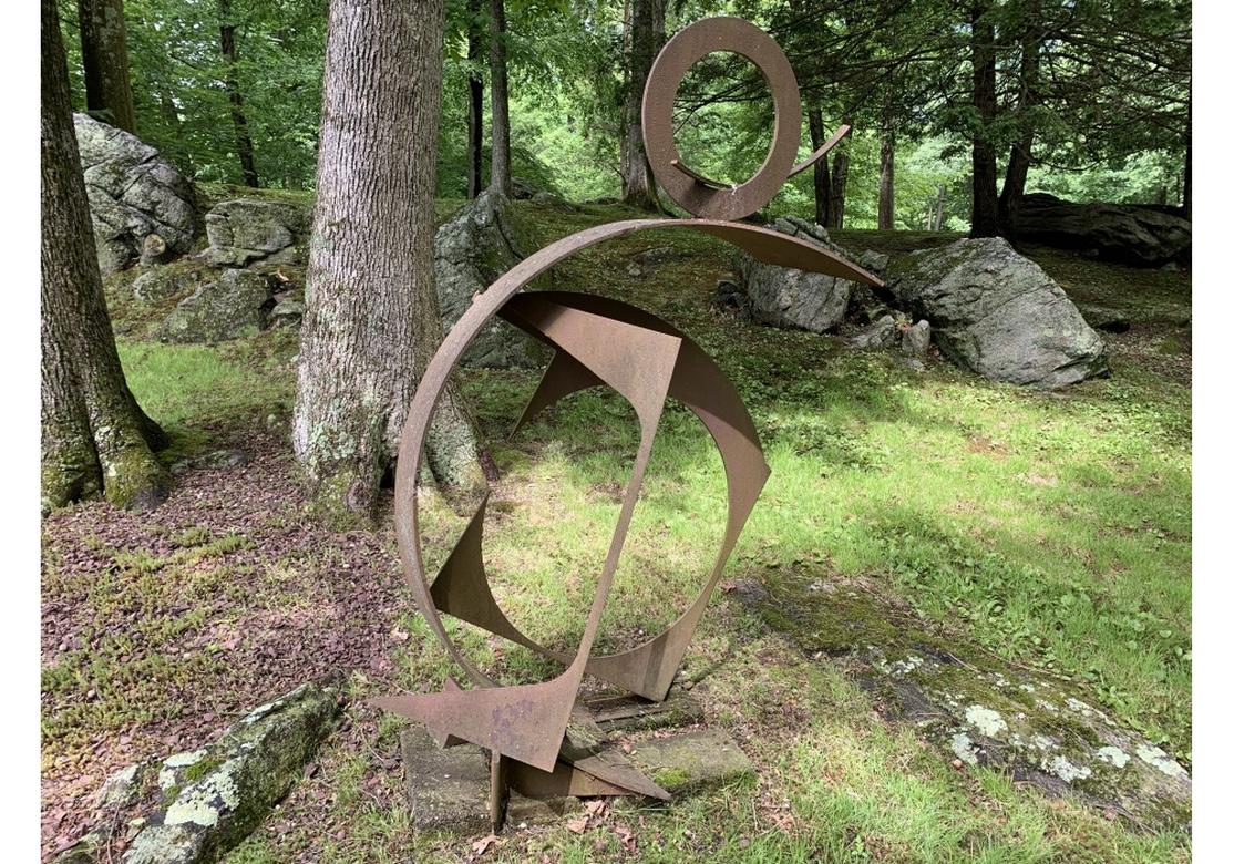 Created by well known multidisciplinary artist Norma B. Flanagan. Originally painted (traces are visible), now worn bare to an Industrial type rust patina. A tall wide sculpture made up of several circular sections set at angles- an open circle sits