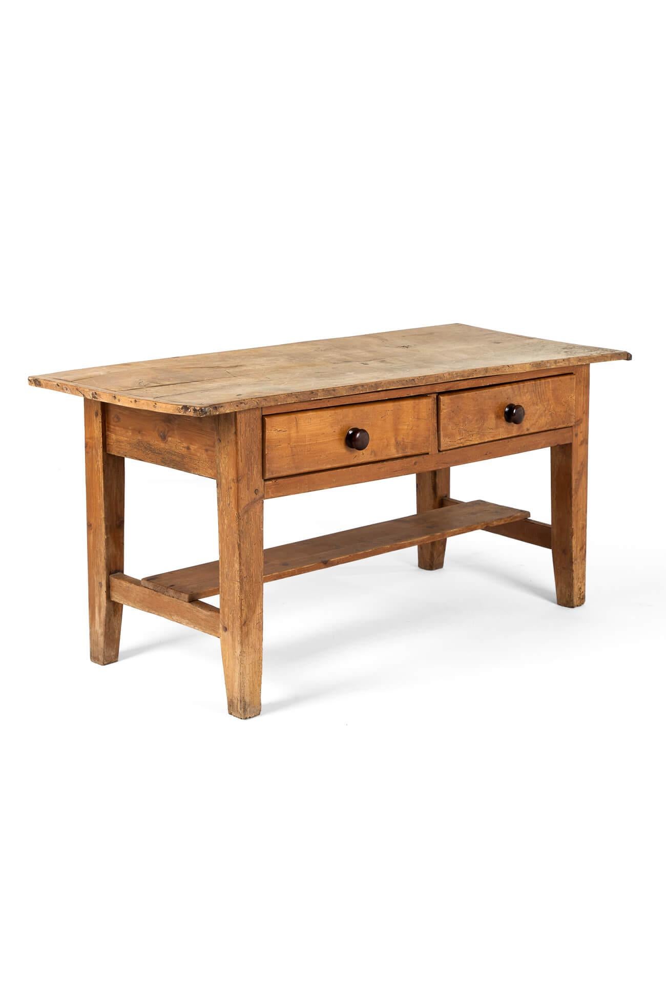 A large pine dairy table with a two plank characterful sycamore top with cleated ends in a lovely naturally sun bleached finish.

The top stretches over two long freize drawers with original ebony handles.

Four block legs united by an H-shaped