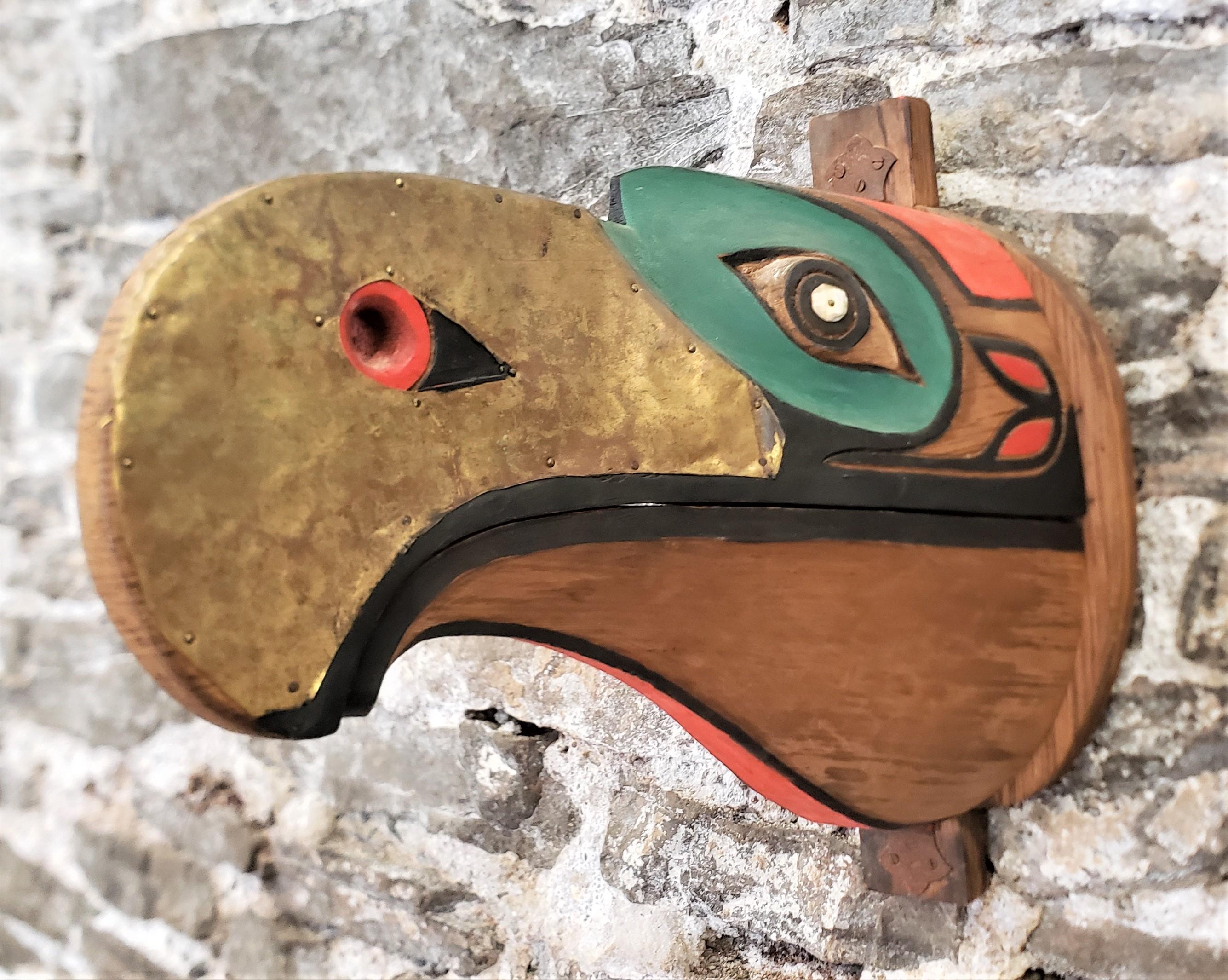 This large and highly decorative articulated hand-carved mask is unsigned, but presumed to have originated from Canada and done in the West Coast Haida style. The mask or wall sculpture is done in a softwood which has been hand-carved and